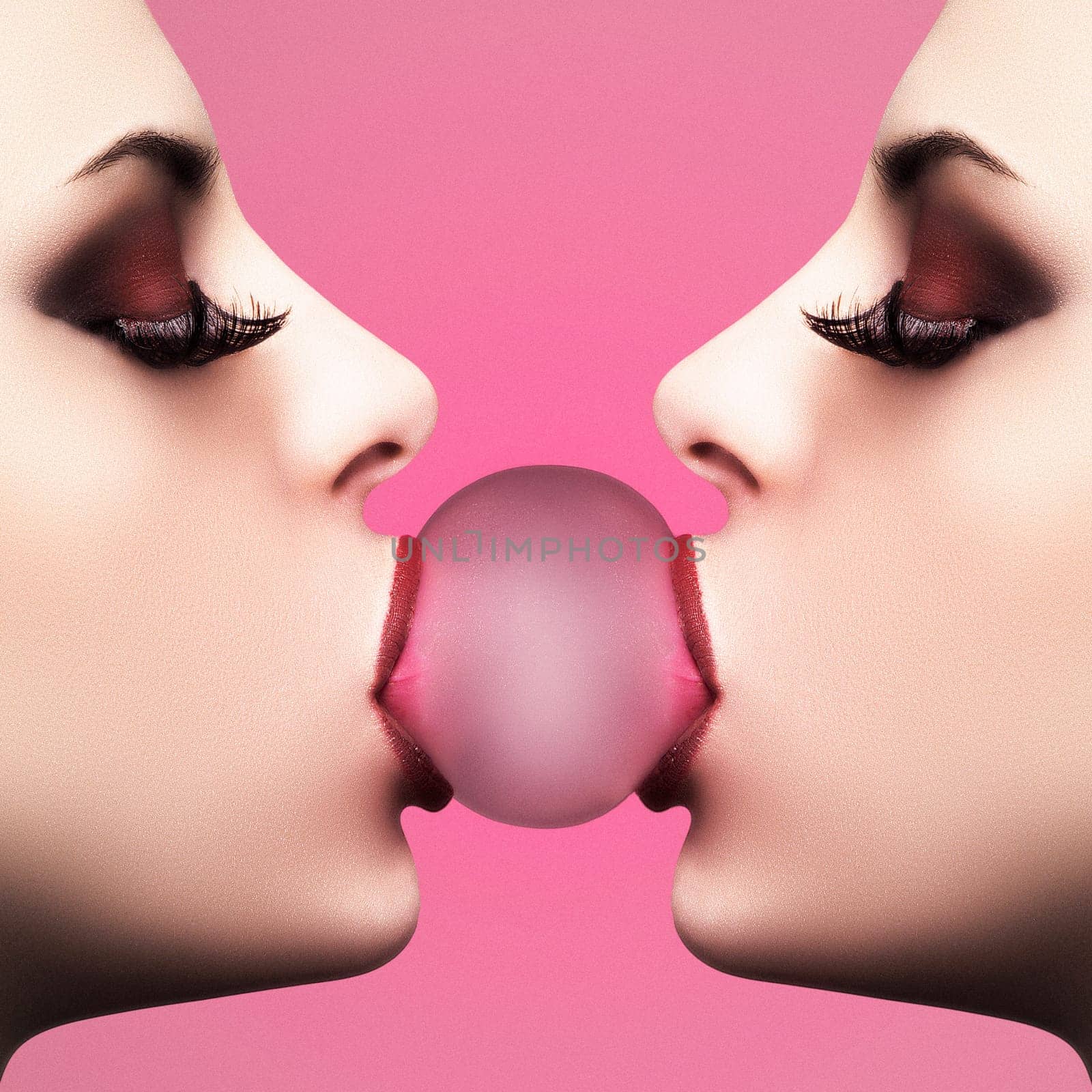 Sexy young woman makes a balloon with a bubble gum against pink background
