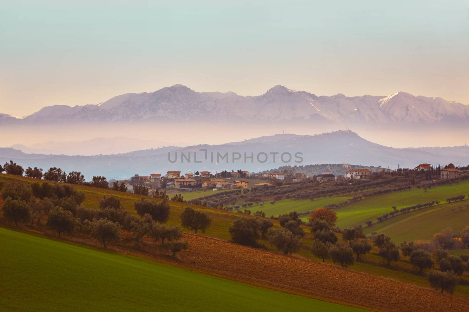 Panorama of the Italian countryside with misty and snowy mountains in distance