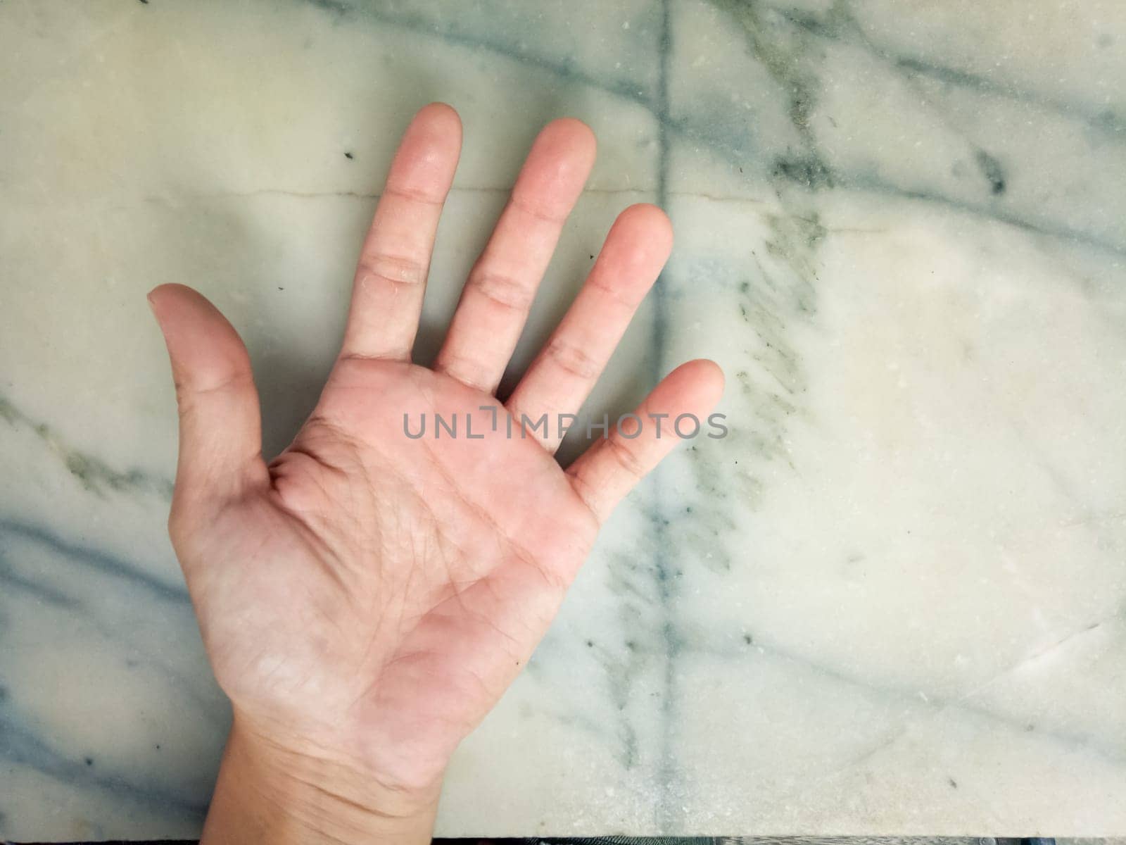 Man open palm hand isolated on white marble background.