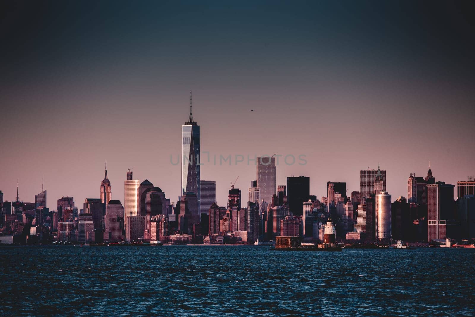 New York City Manhattan downtown skyline at dusk with skyscrapers illuminated over Hudson River panorama. Vertical composition.