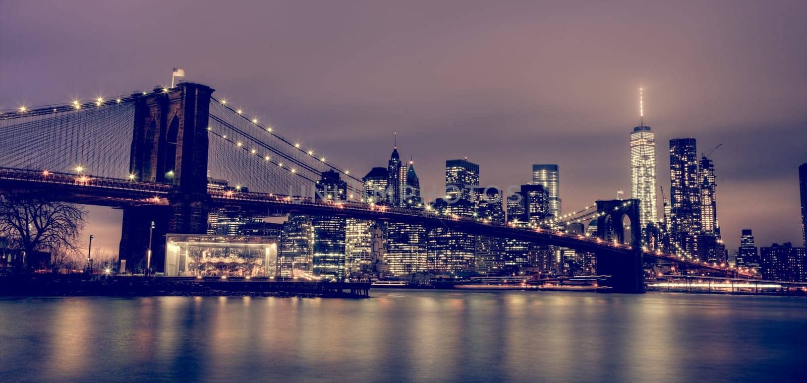 Brooklyn bridge and New York City Manhattan downtown skyline at dusk with skyscrapers illuminated over East River panorama. Copy space.