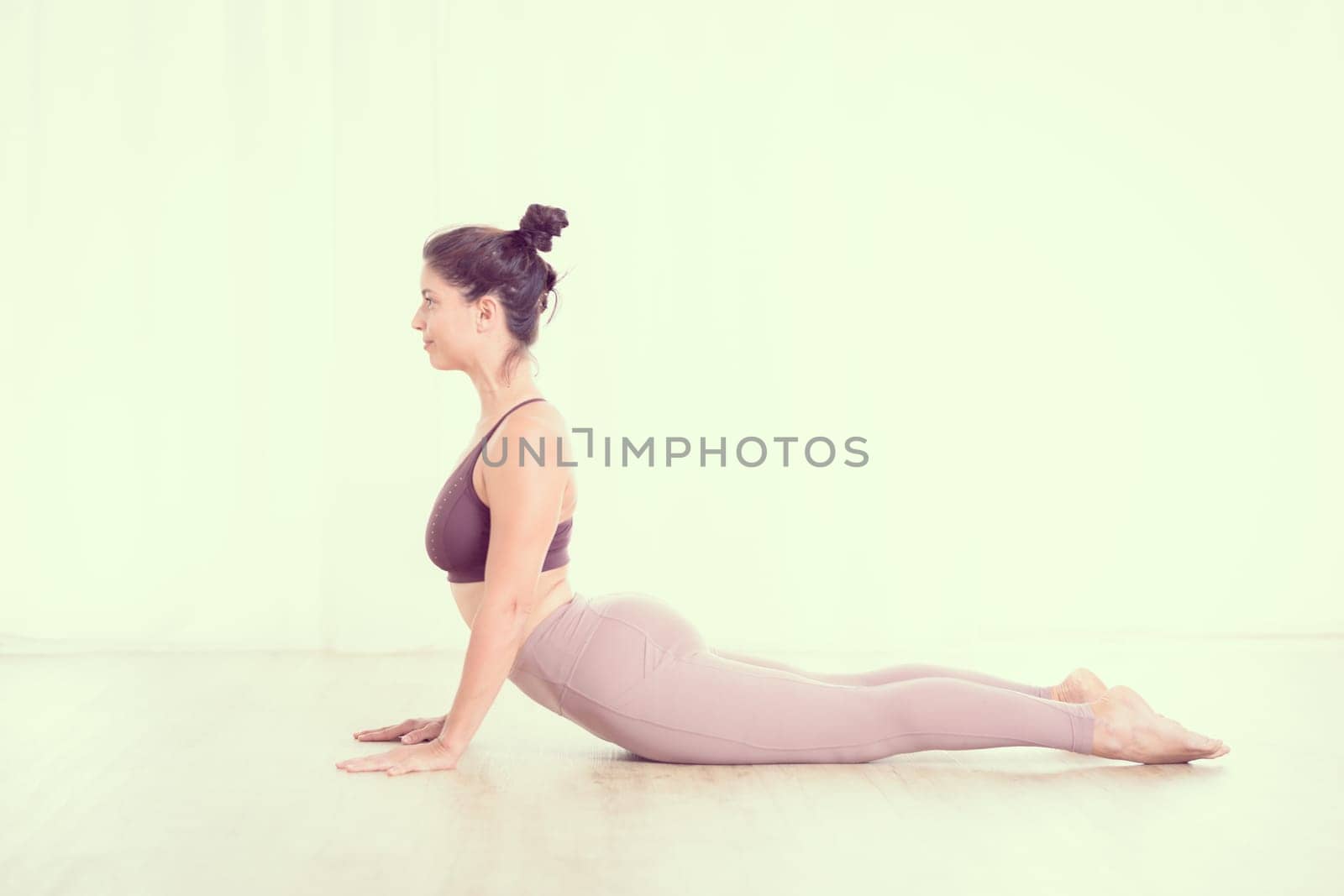 Portrait of gorgeous active sporty young woman practicing yoga in studio. Beautiful girl practice Sasangasana, rabbit yoga pose. Healthy active lifestyle, working out indoors in gym.