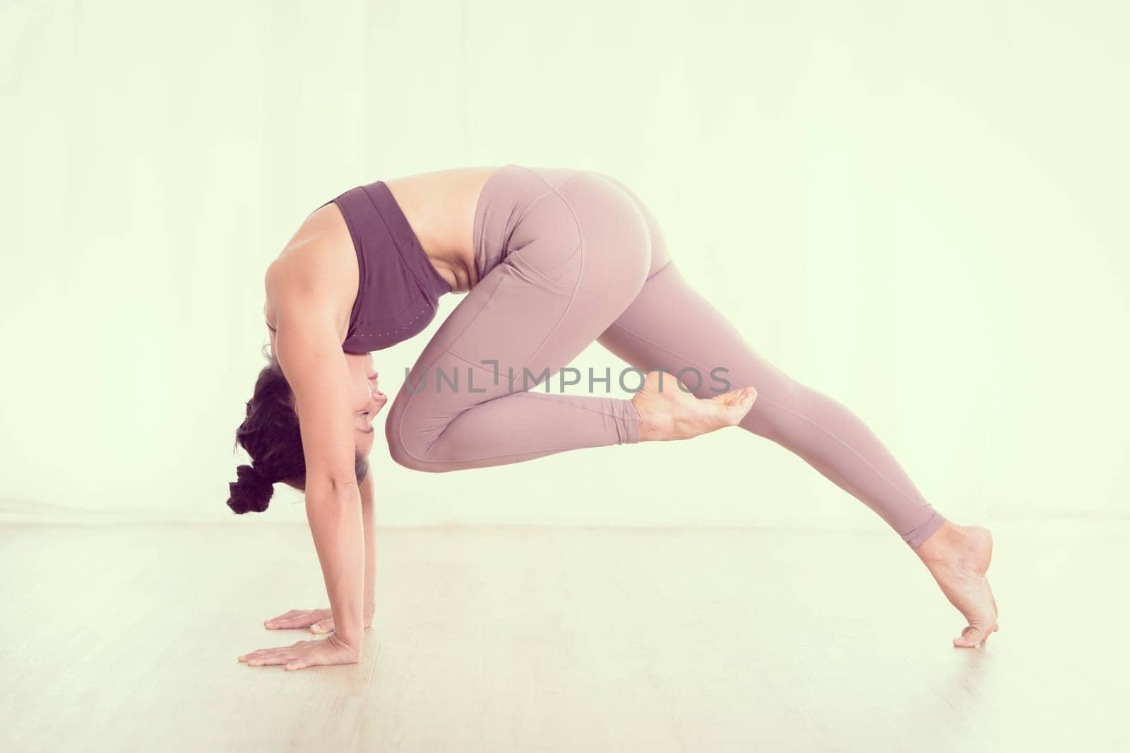 Portrait of gorgeous active sporty young woman practicing yoga in studio. Beautiful girl practice Sasangasana, rabbit yoga pose. Healthy active lifestyle, working out indoors in gym.