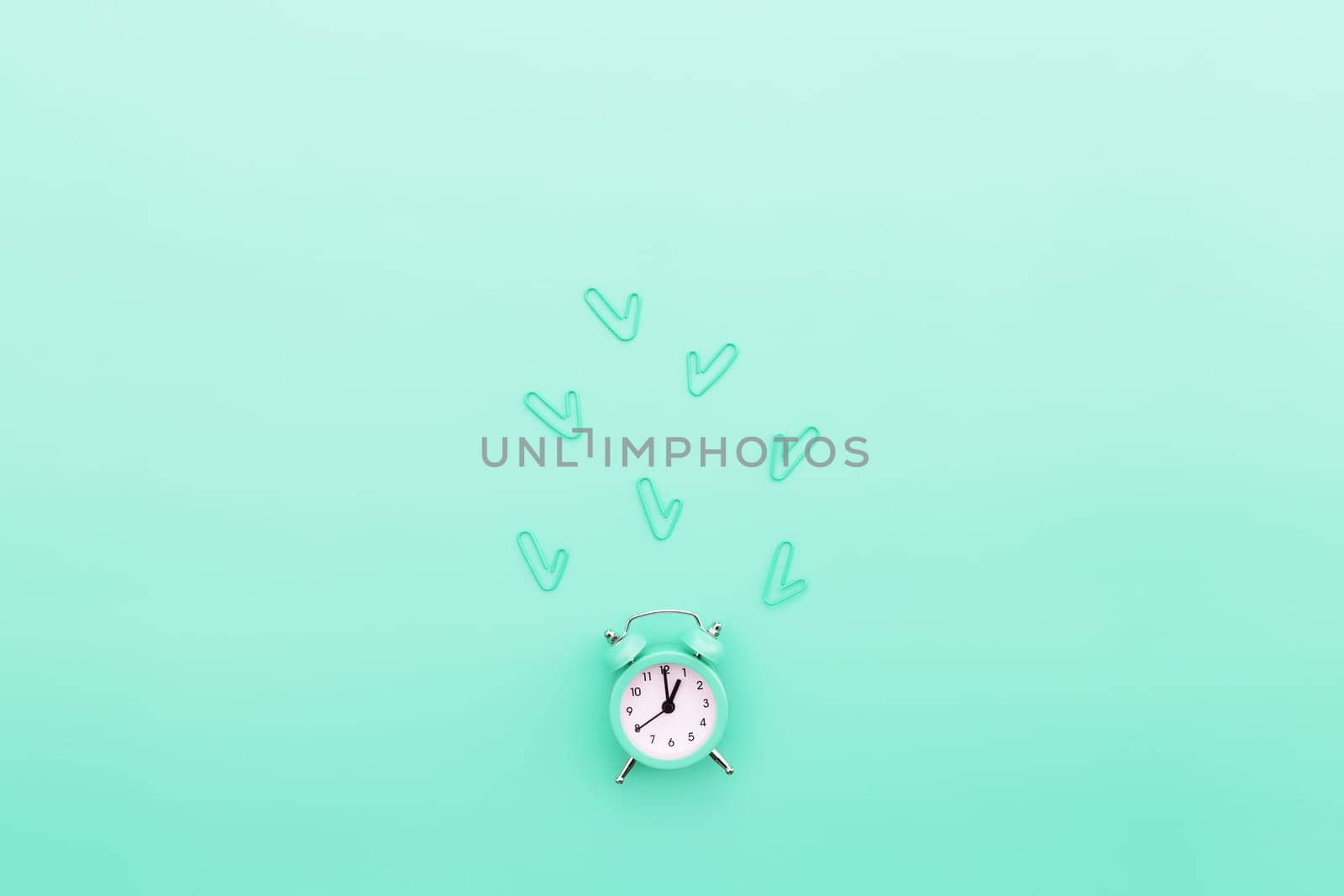 Back to school, office work conceptual flat lay with alarm clock, clips and copy space area for text. Concept of time to work, be in time and wake up early idea. Turquoise background and alarmclock