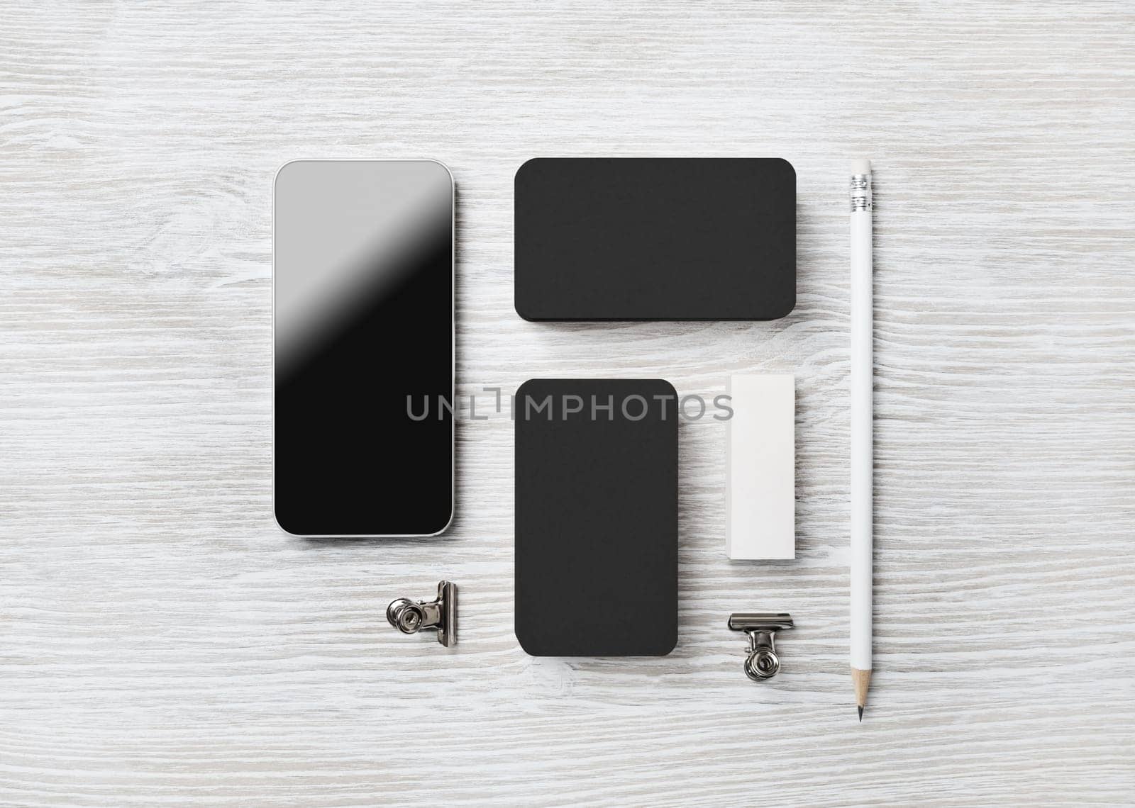 Blank black stationery set and smartphone on light wood table background. Branding mock up. Flat lay.