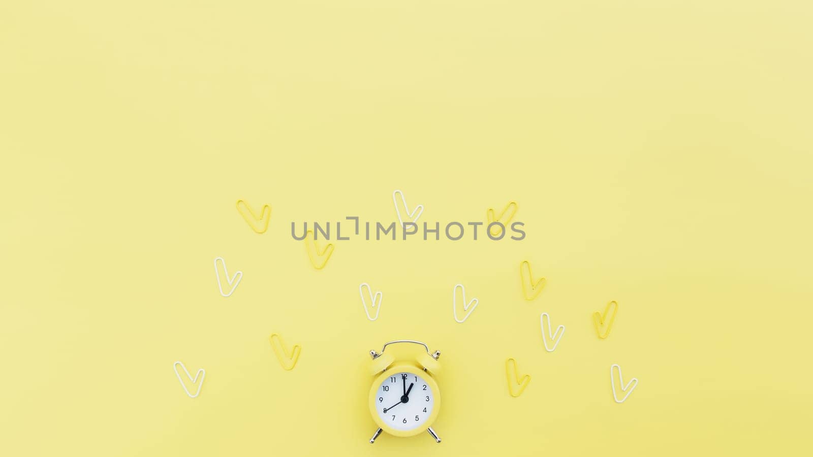 Back to school, office work conceptual flat lay with alarm clock, clips and copy space area for text. Concept of time to work, be in time and wake up early idea. Yellow background and alarmclock