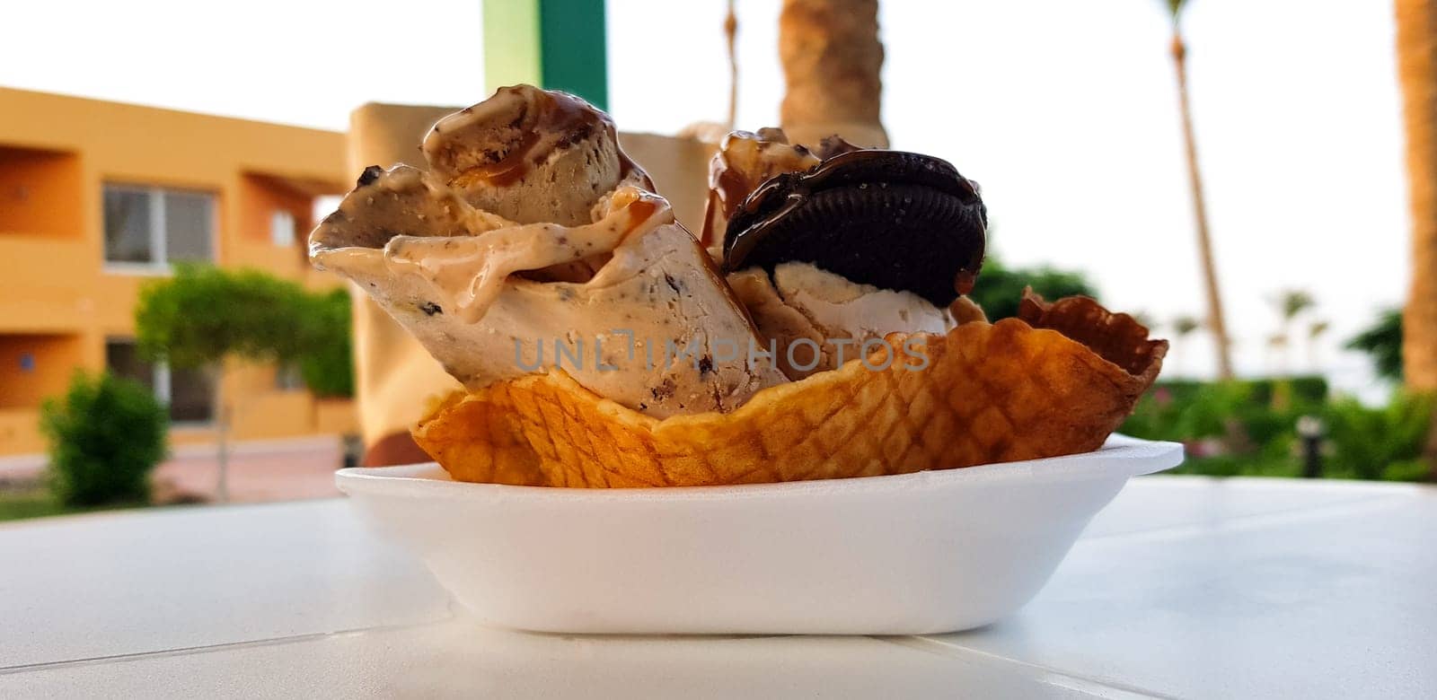 A serving of fried ice cream with caramelized banana cream cookies on a white table summer cafe.