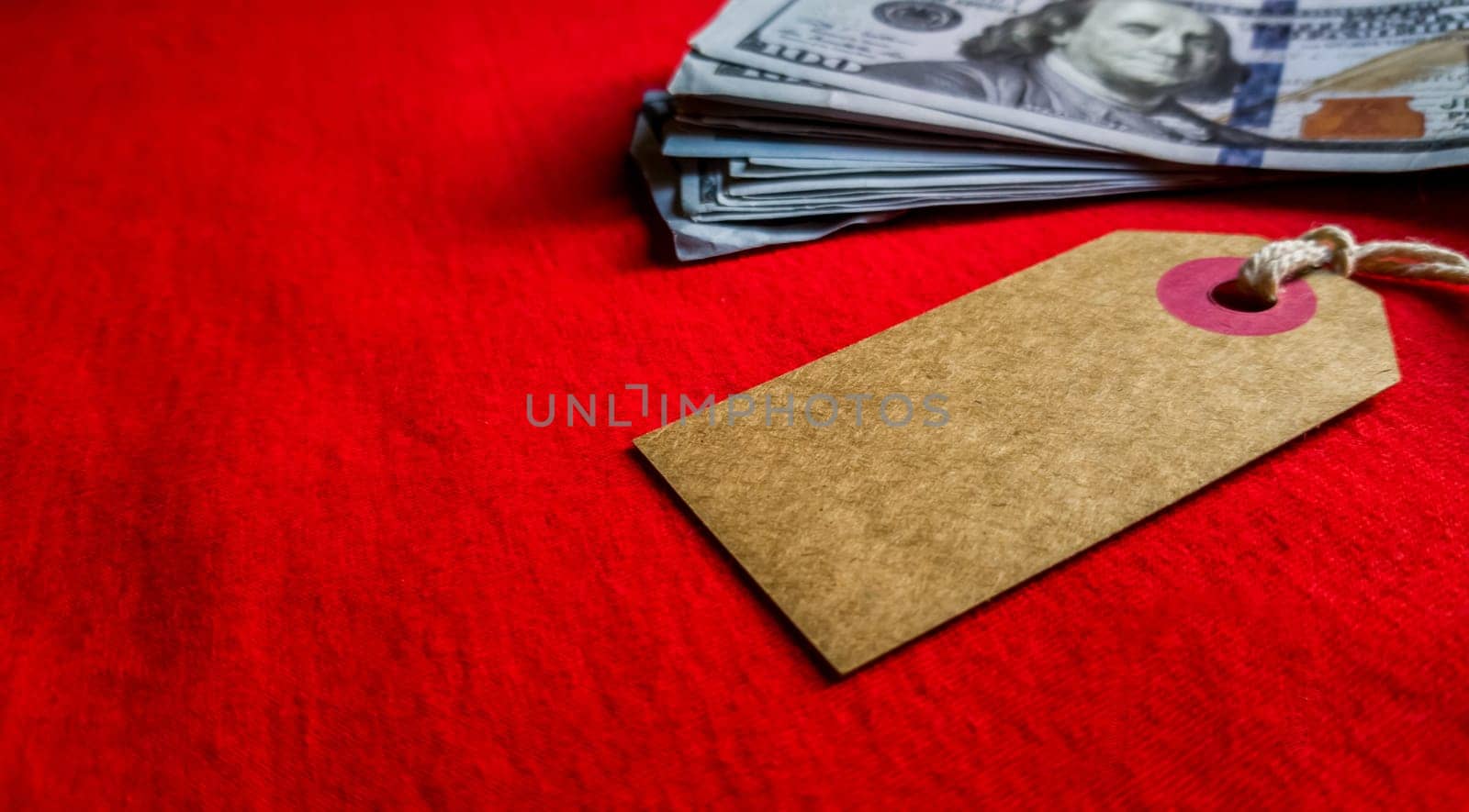 Empty cardboard tag for the inscription Black Friday with American dollars on a red background. Background, holiday concept. Black Friday - International Day of Shopping, Promotions, Discounts, Sales. Sales season is the fourth Thursday of November. Copy space, place for text.