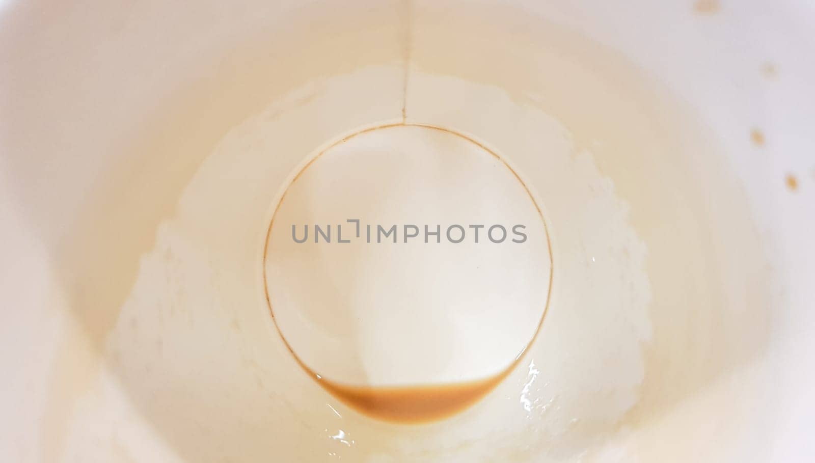 Leftover food on a paper plate and empty dirty paper coffee cup on a wooden table in a fast food cafe.