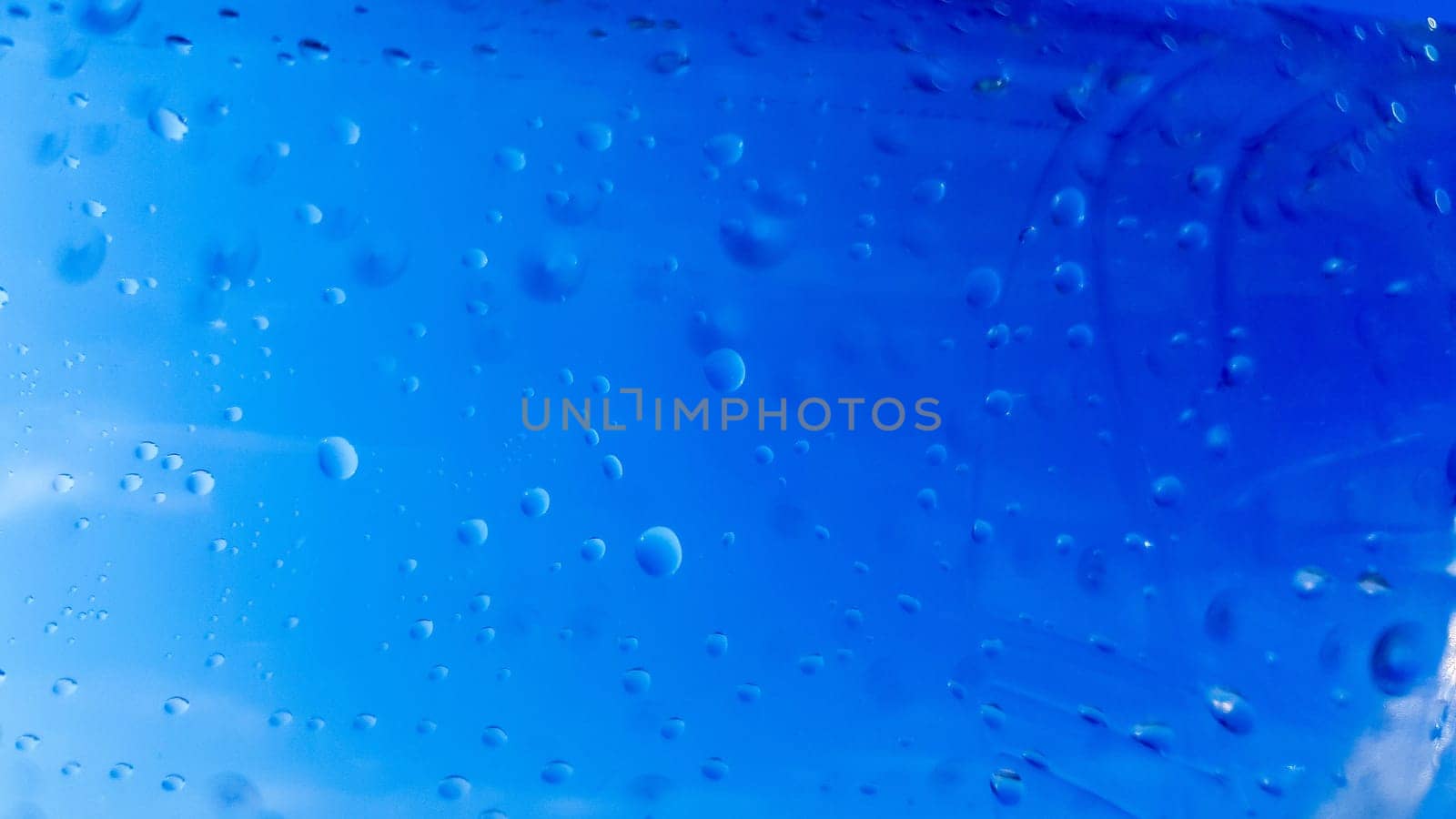 A lot of drops of water inside a plastic bottle. Blue background with water drops.