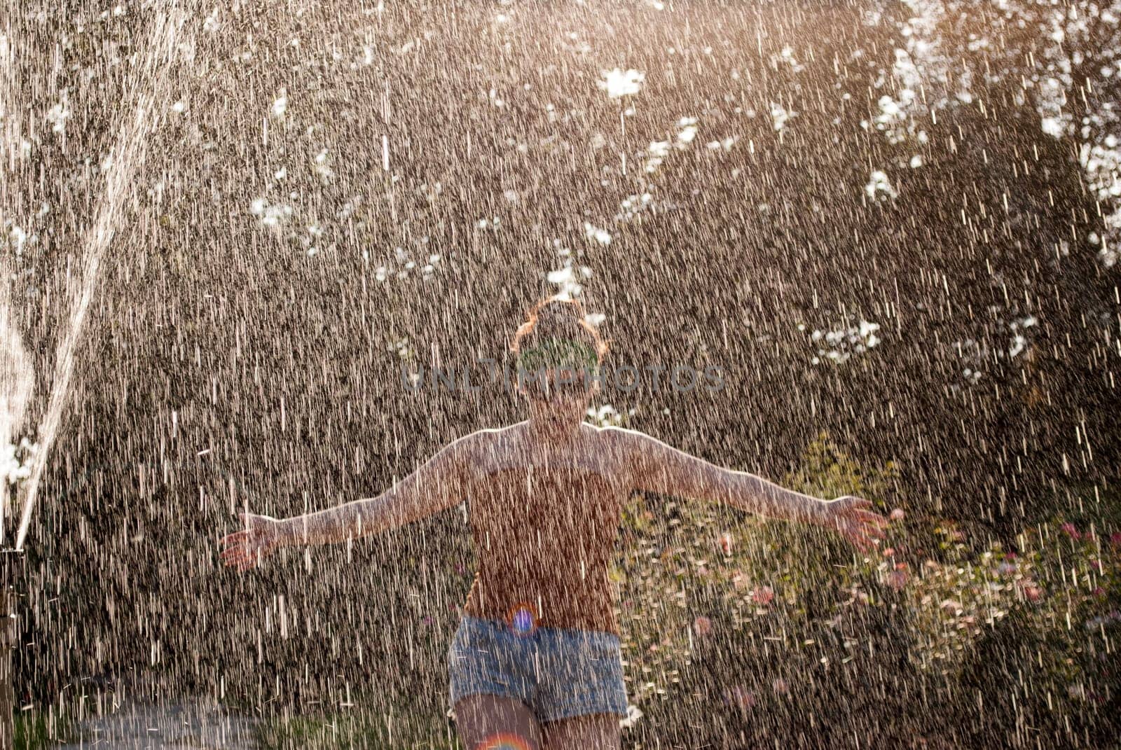 happy girl runs through a fountain in a green park in the sunshine.