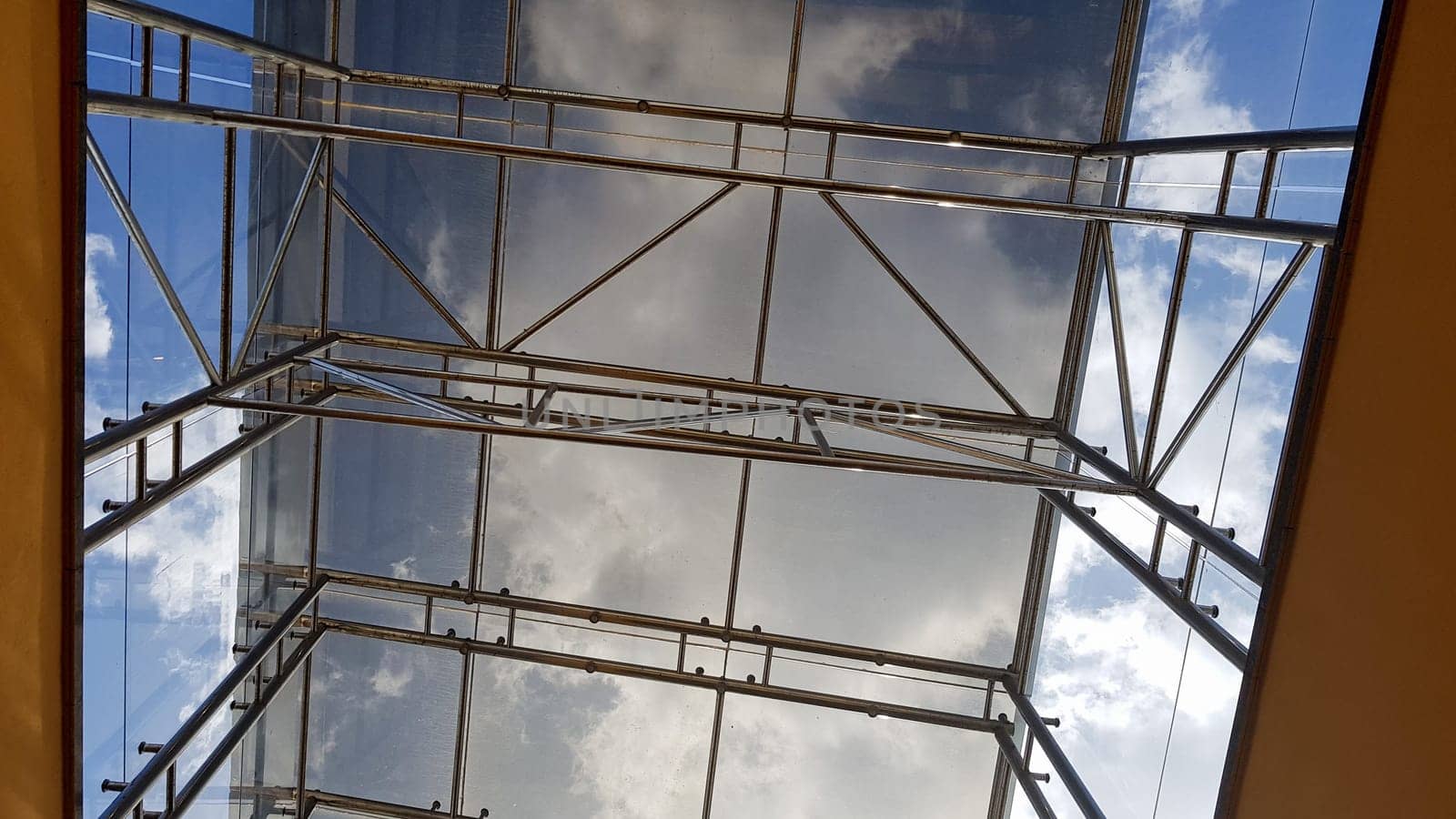 Structural glazing of the facade. Abstract background with glass ceiling elements in a modern building. view of the blue sky through a glass window, separated by lattice elements