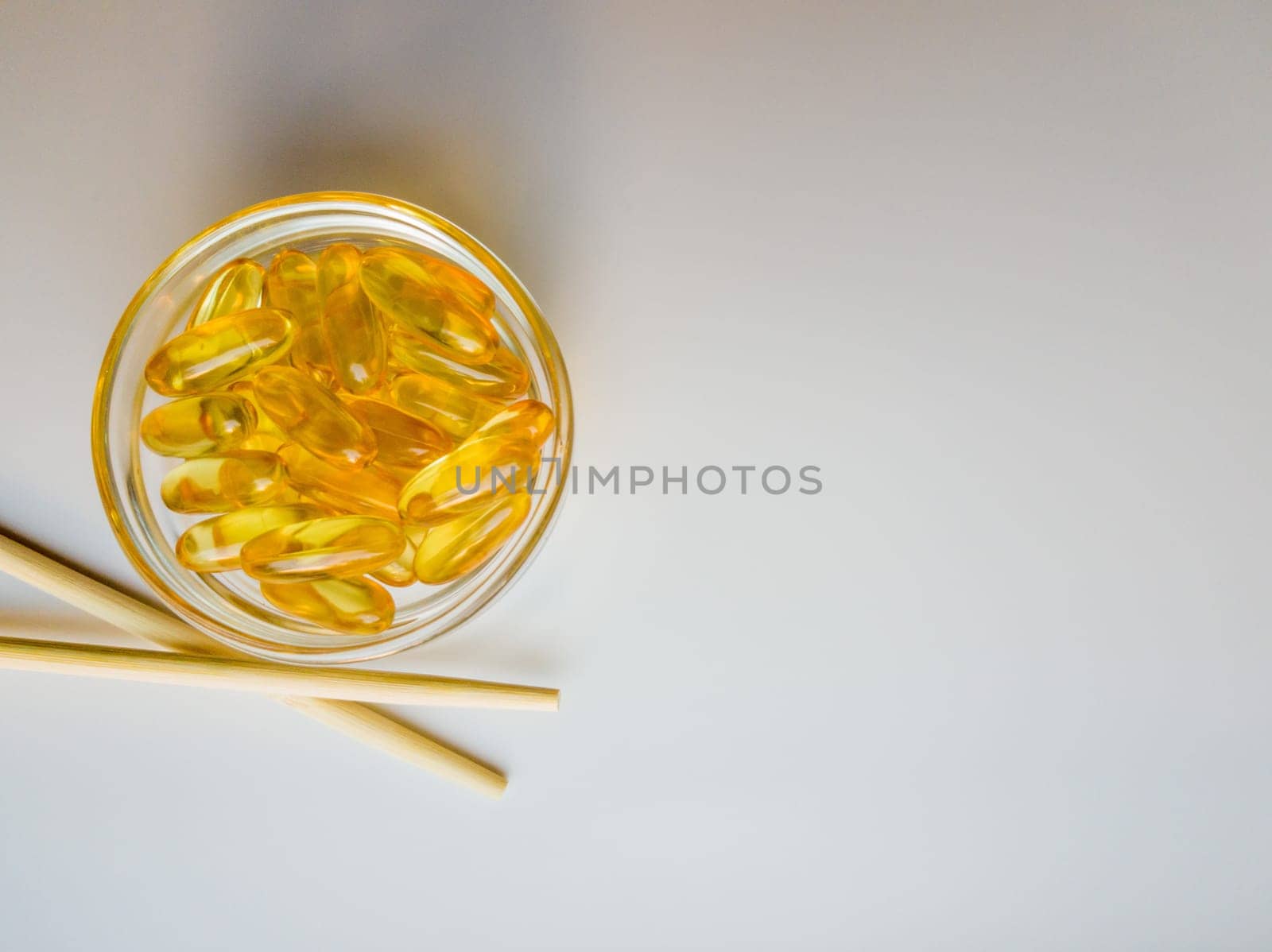 Fish oil capsules on a saucer with chopsticks. Bunch of vitamin omega 3 pills on a white background. Close-up, top view, high resolution product. Metabolism in the body. Body calcium