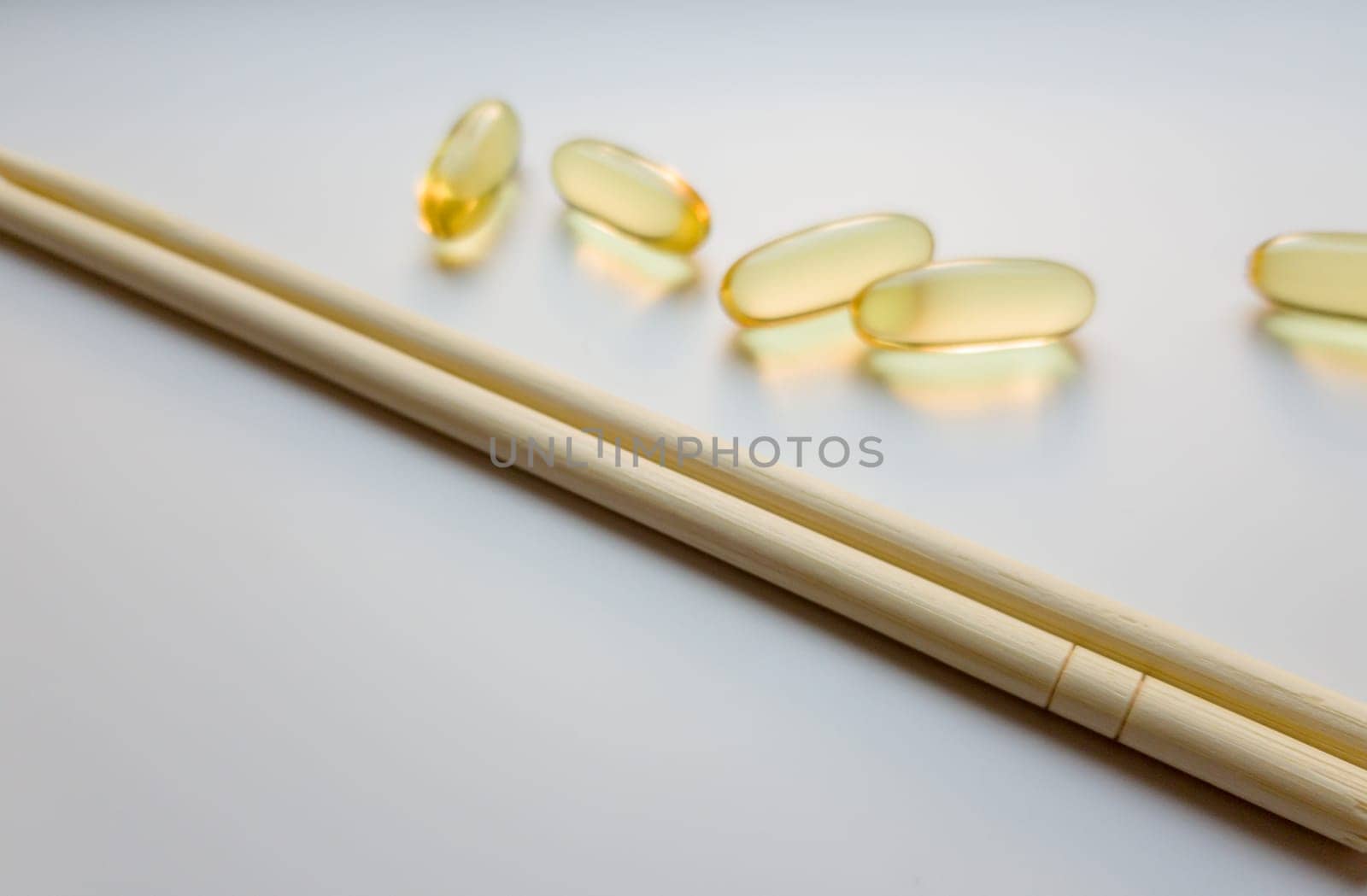 Fish oil capsules with Chinese chopsticks. Omega 3 on a white background. High Resolution Product. Food supplement. Vitamins for a healthy lifestyle. Fatty acid. Metabolism in the body