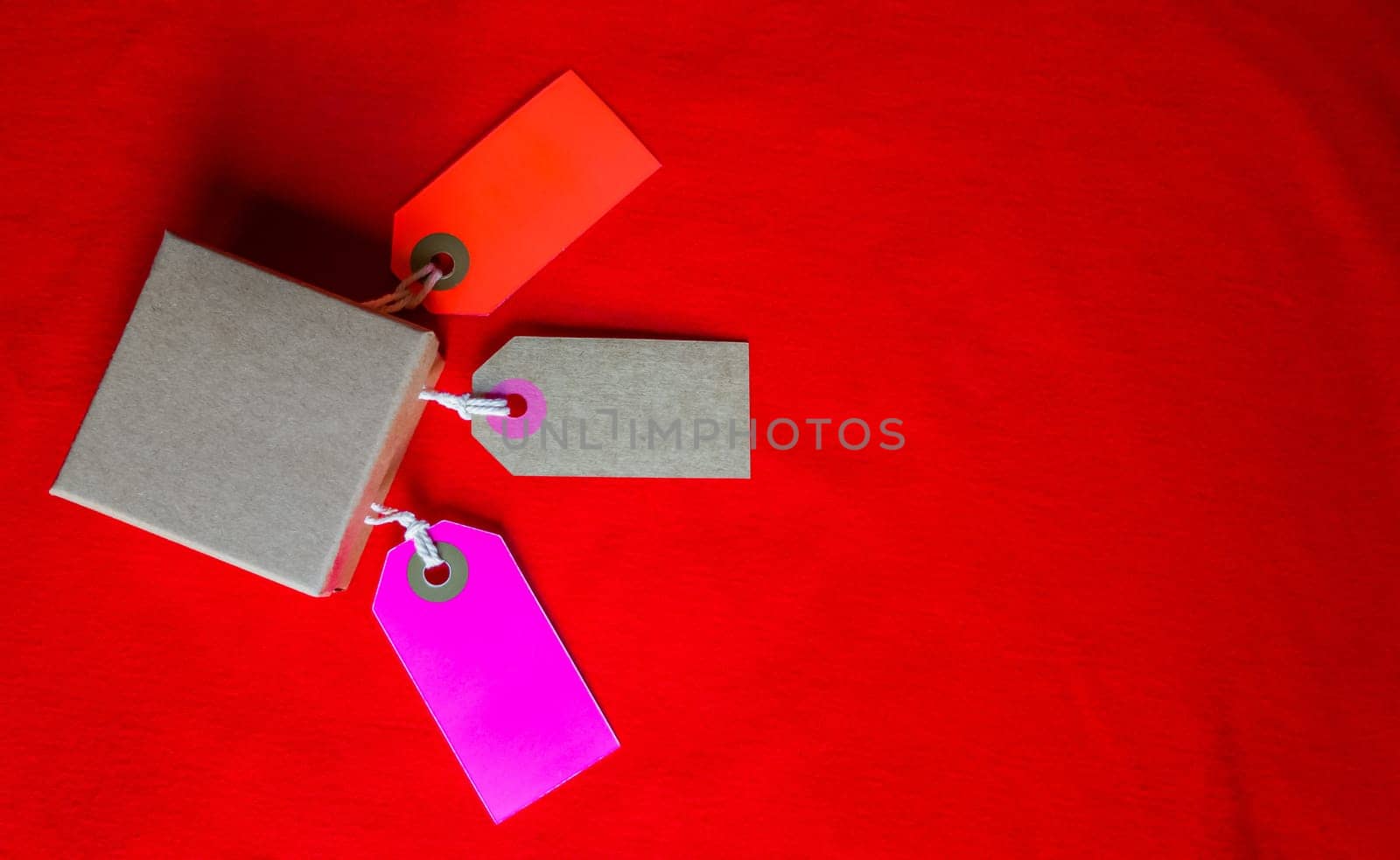 Cardboard boxes with a tag. Brown packing box with blank label and copy space on red backdrop.