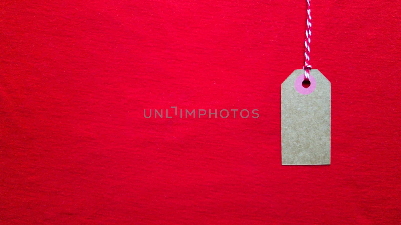 Red tag tag hanging on a red rope on a red background. Copy space, place for text, flat lay