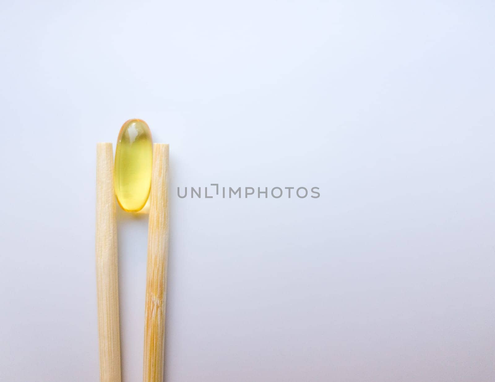 Fish oil capsules with Chinese chopsticks. Omega 3 on a white background. High Resolution Product. Food supplement. Vitamins for a healthy lifestyle. Fatty acid. Metabolism in the body