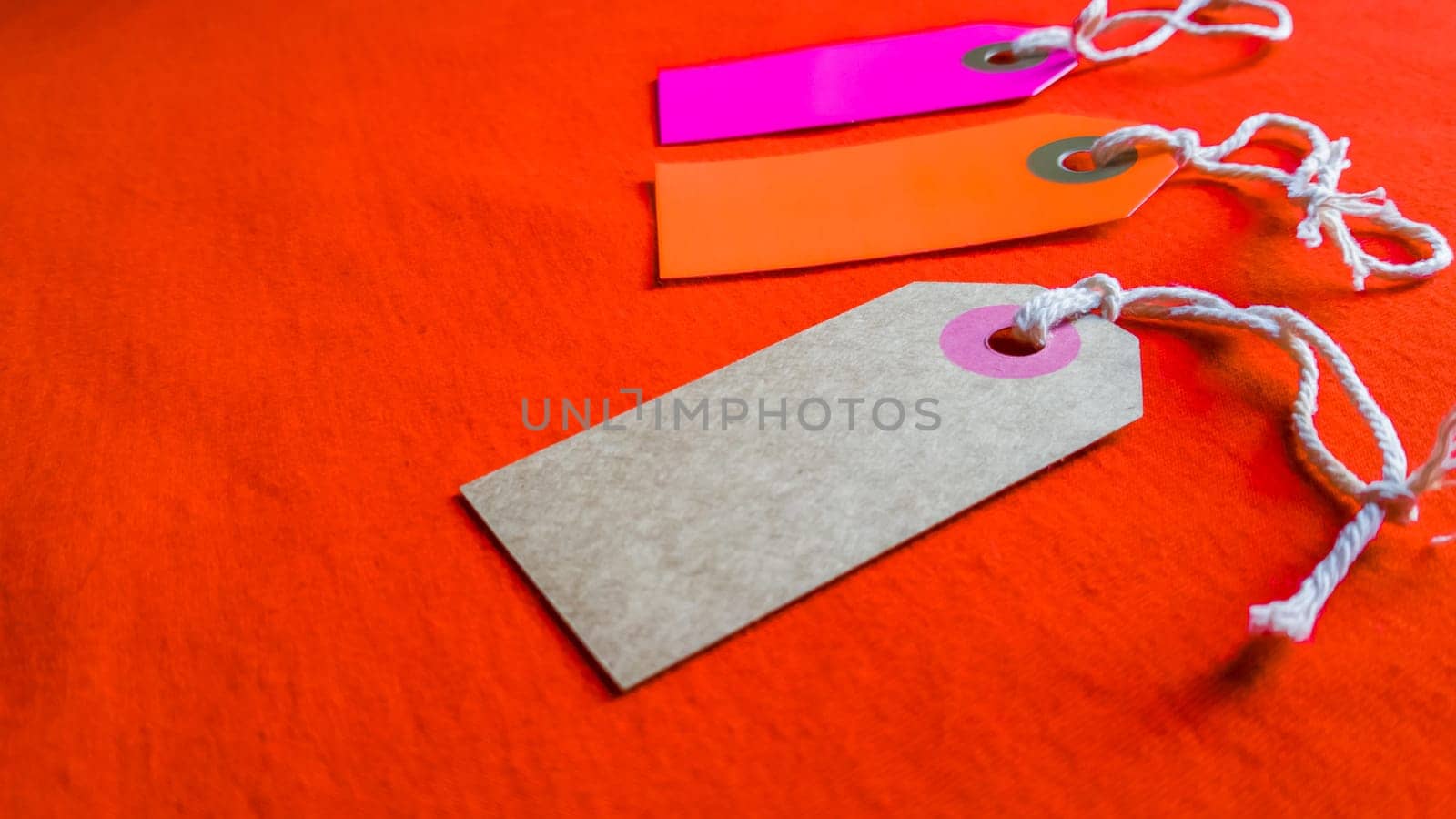 three colored tags on a white rope, red background.