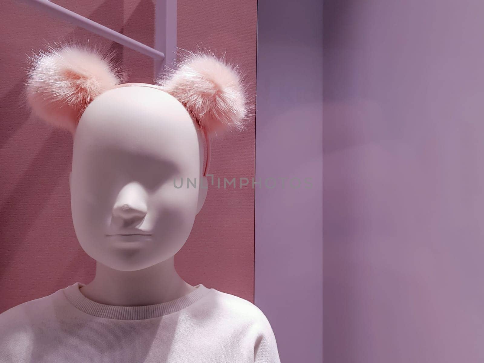 Portrait of a white mannequin girl on a background of bright colorful warm pink shades. Little doll in a shop window. Boutique with a young mannequin. Department of children's clothing. Face close up.