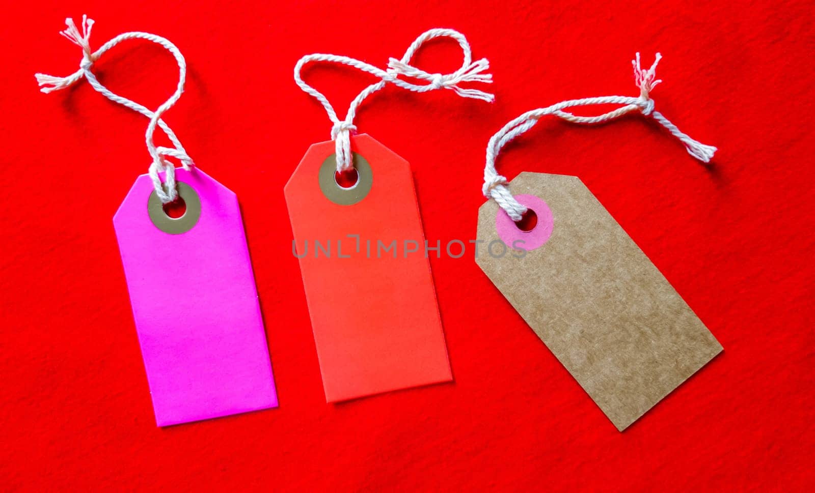 three colored tags on a white rope, red background.