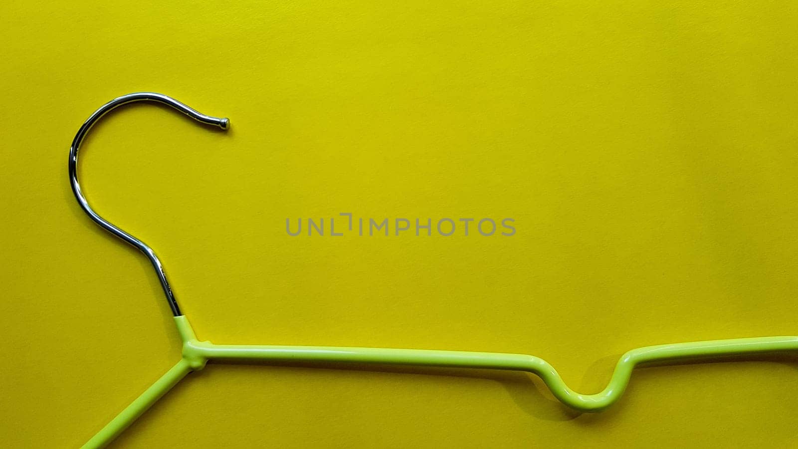 Hanger for clothes on a yellow background. Green hanger. Background with copy space. Black friday, shopping day.