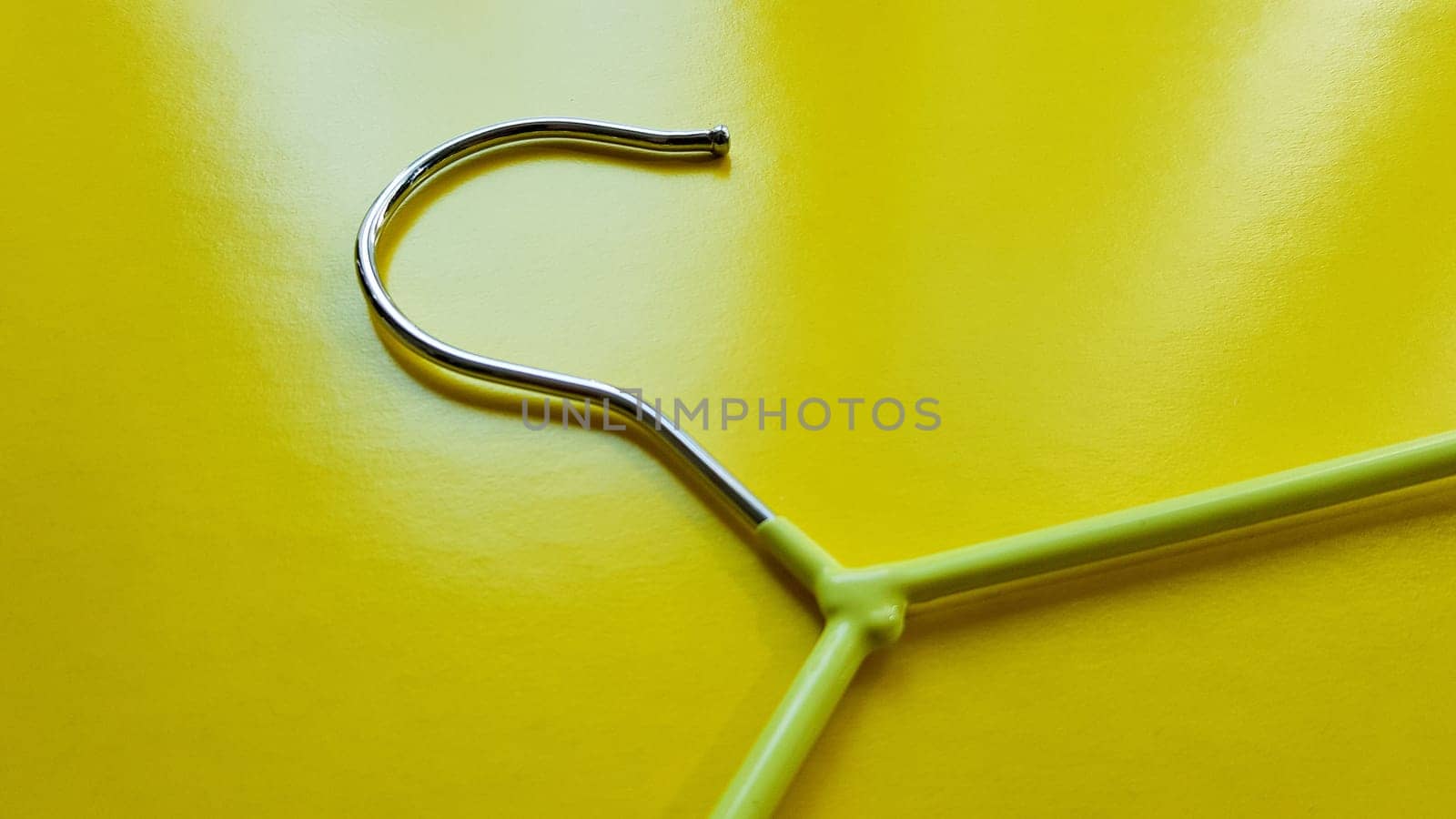Hanger for clothes on a yellow background. Green hanger. Background with copy space. Black friday, shopping day.