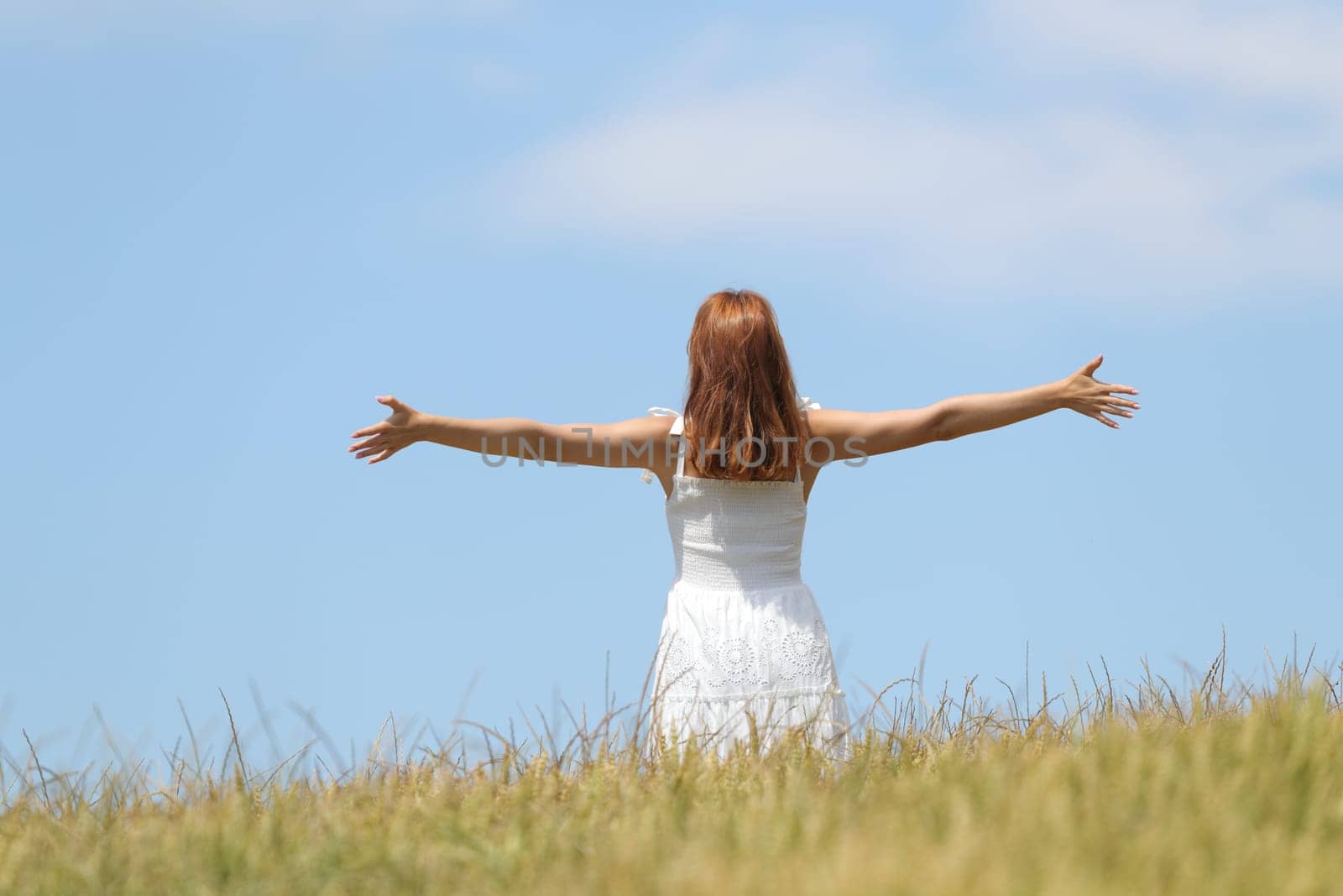Happy woman celebrating outstretching arms in a field