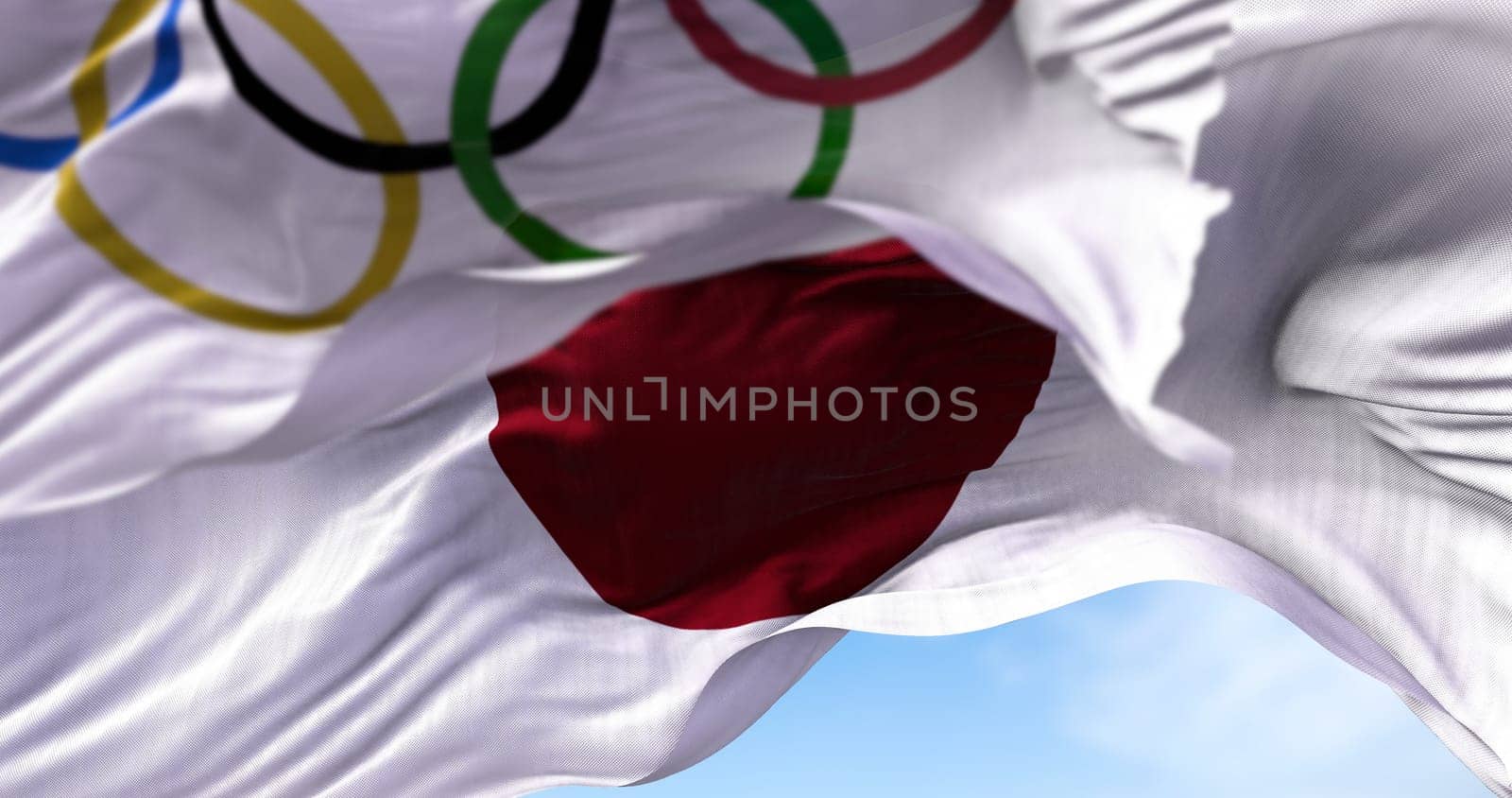 Tokyo, Japan, July 2021: The national flag of Japan waving with the Olympic flag blurred in the foreground. Tokyo 2020 olympics games were postponed to 2021 due to the covid-19 pandemic