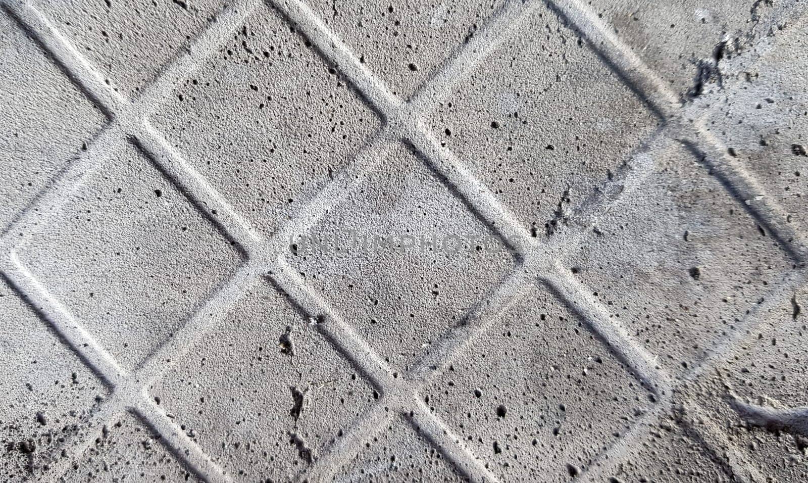 Background of an old darkened shabby and scratched gray concrete floor with traces of floor tiles. Concrete texture, trace of fallen off tiles of dark gray color, mesh structure, concrete pieces.