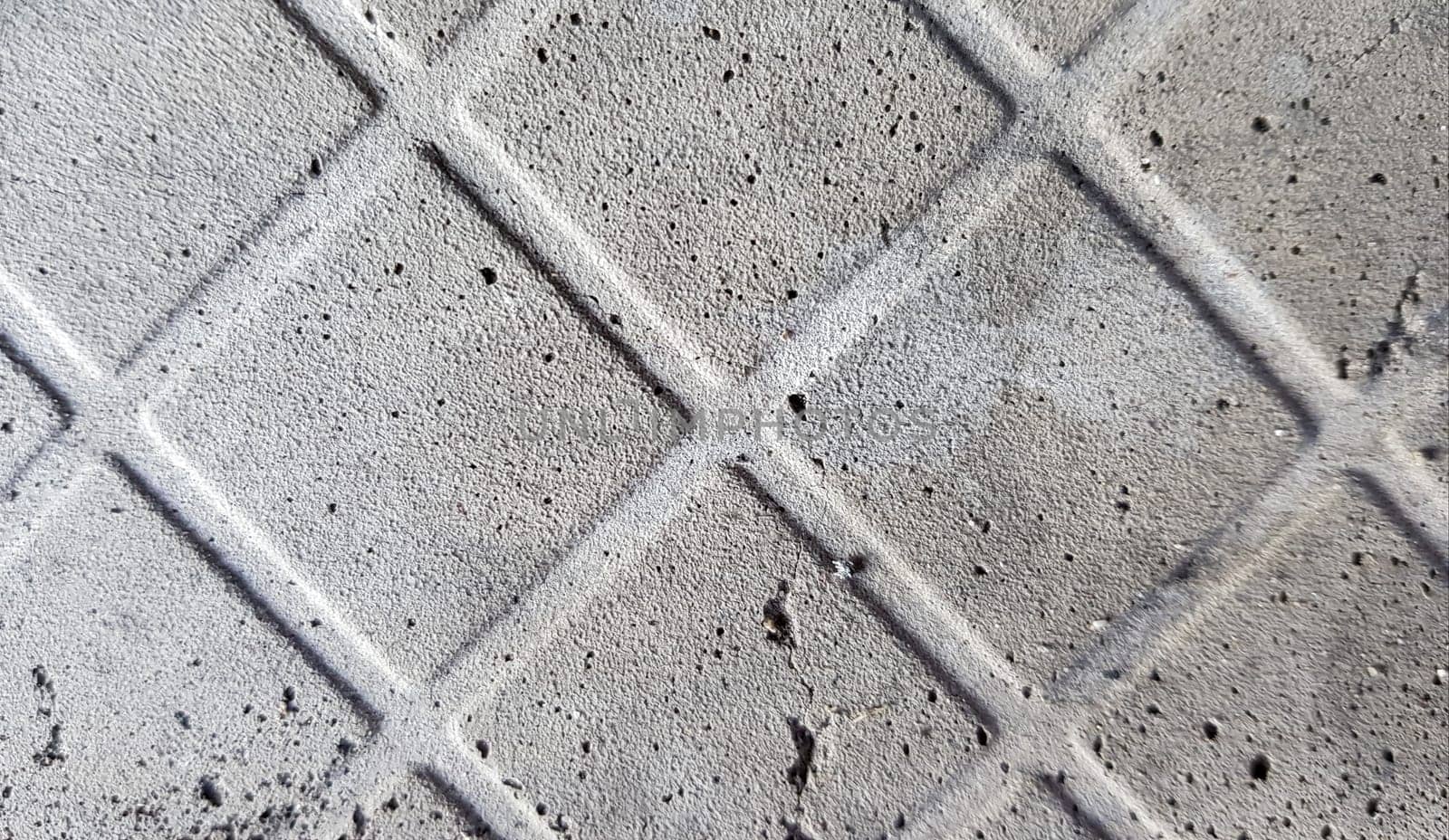 Background of an old darkened shabby and scratched gray concrete floor with traces of floor tiles. Concrete texture, trace of fallen off tiles of dark gray color, mesh structure, concrete pieces.