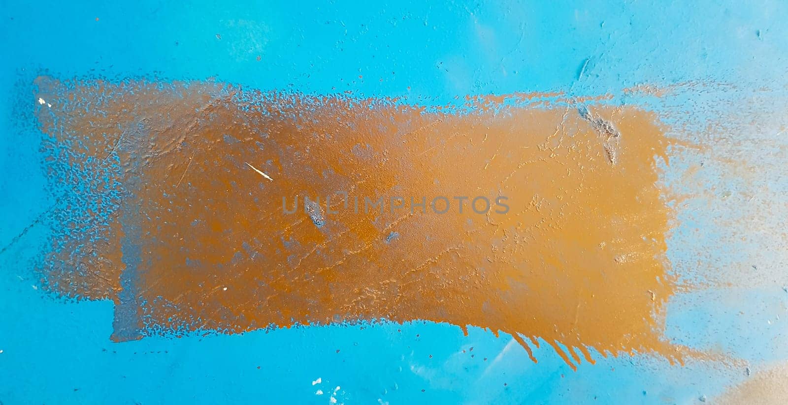 Blue shabby paint background on rusty iron. Blue metal wall with a brown smear of rectangular paint in the center.
