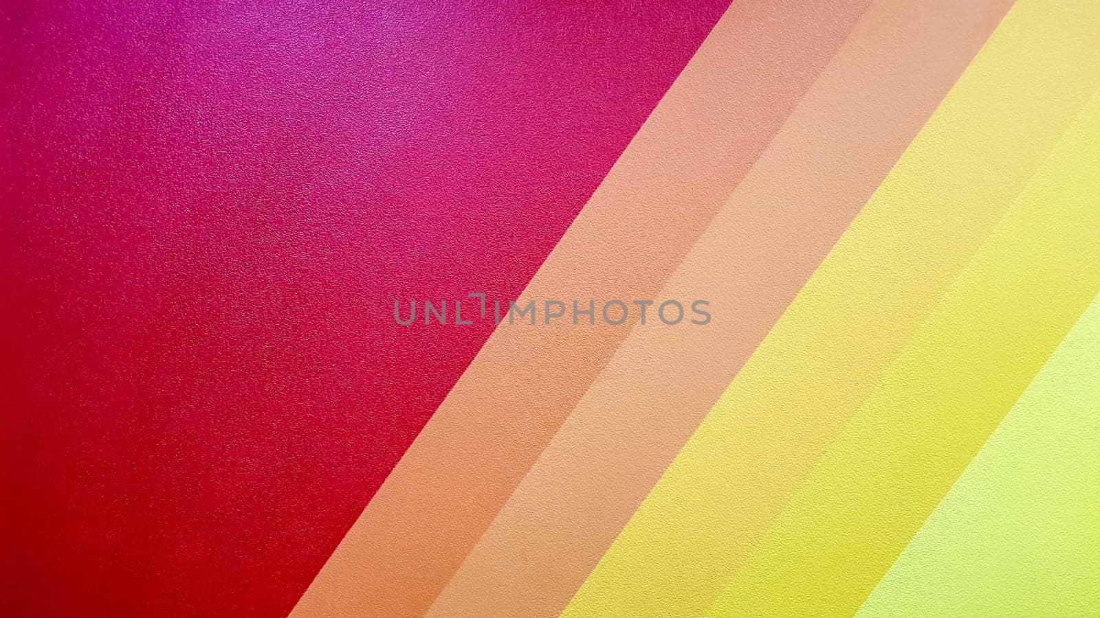 The wall is painted in red, pink, orange, yellow color with diagonal lines. Colorful background for your text and message with copy space