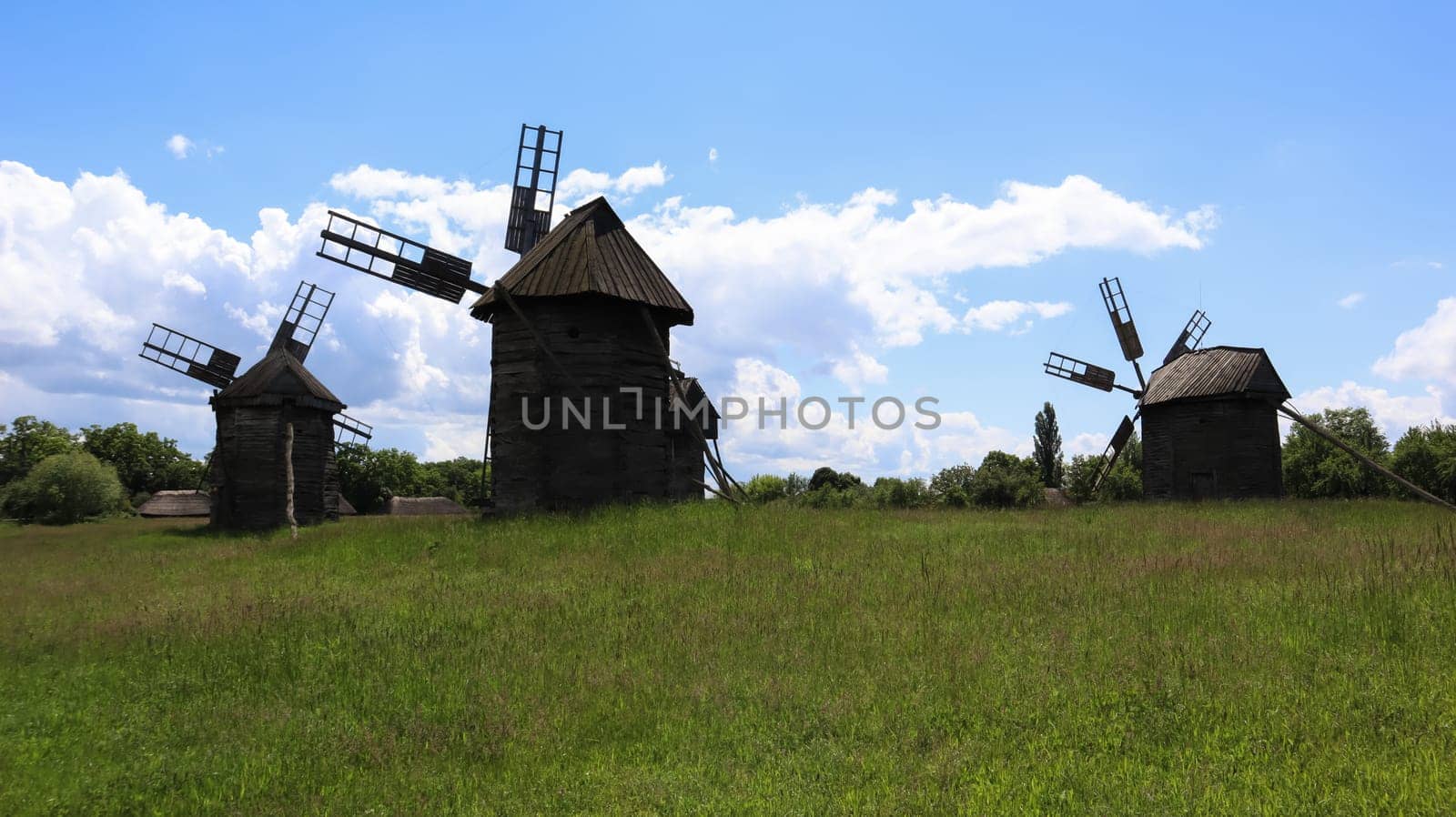 Ukraine, Kiev - June 11, 2020. Old Ukrainian wooden windmills of the XIX century. Summer outdoor landscape. Open-air museum of folk architecture and life, Pirogovo, Ukraine. Tourism and travel
