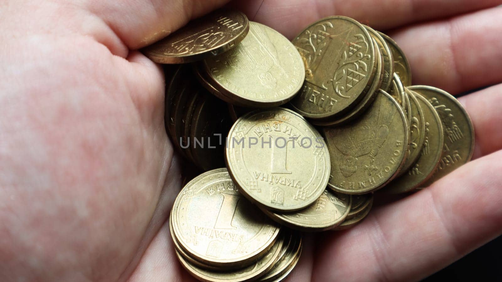 Ukrainian metal coins with a face value of 1 hryvnia in the palm of a male hand. A handful or pile of coins in the hands. Concept of retirement, savings and wealth, credit and mortgage, poverty