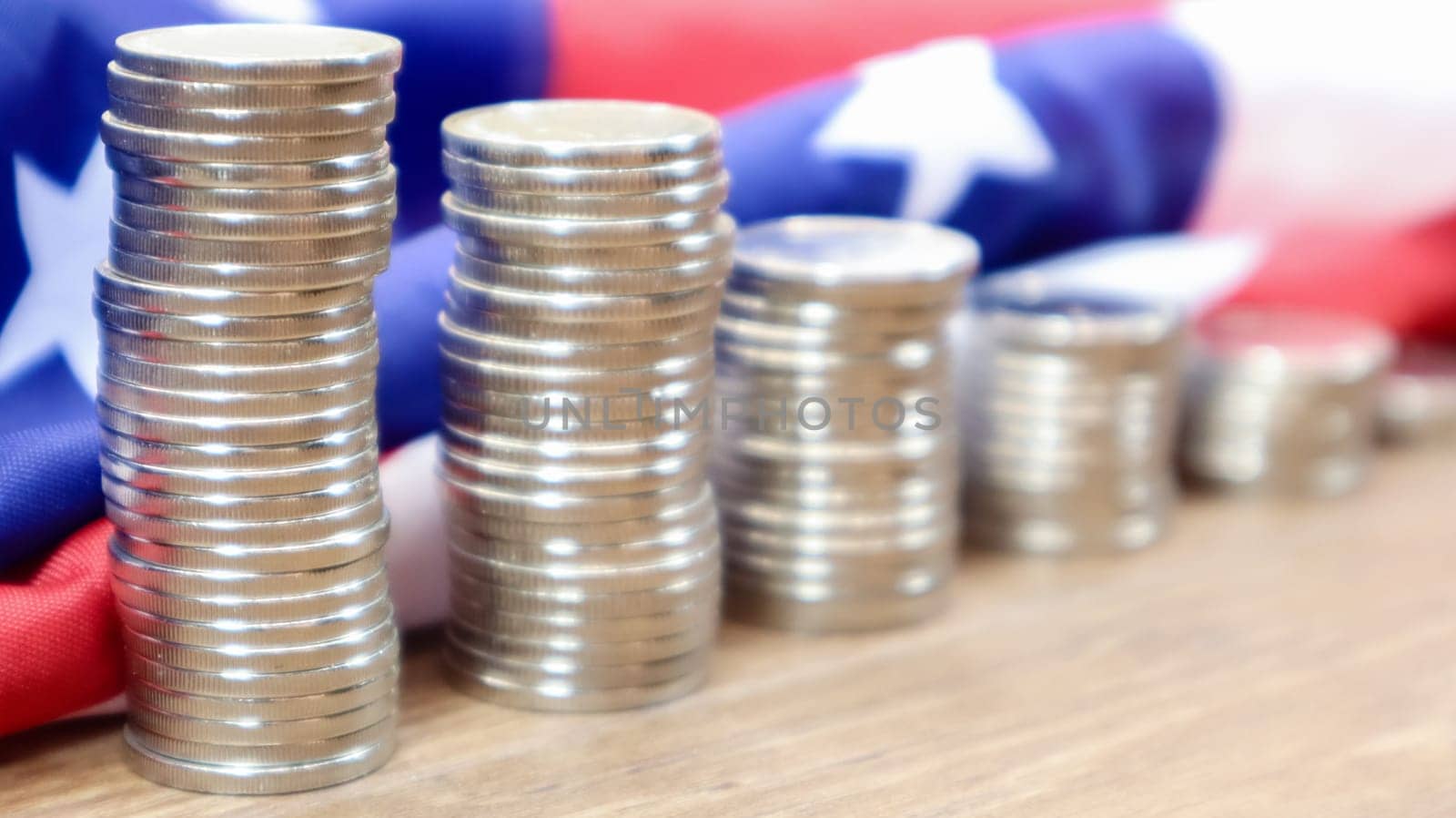 American coins with the flag of the United States of America. Investment concept, business finance and money saving. US coins stacked against the background of the American flag. Selective focus