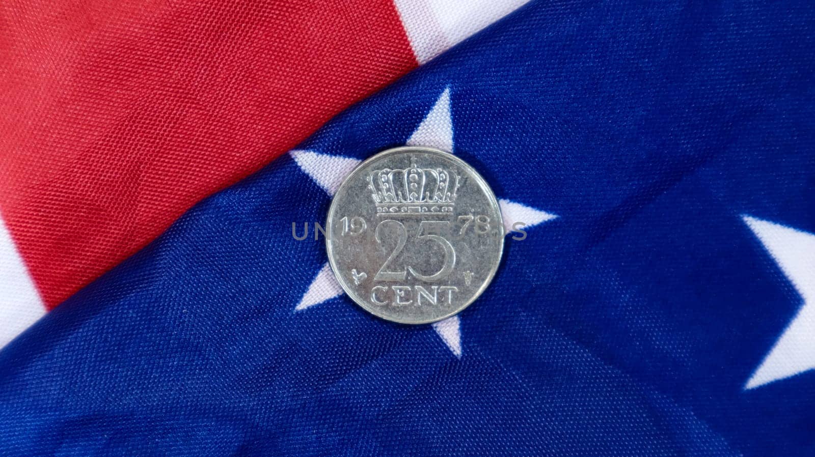 A 1 cent American dollar coin lies on the American flag. The currency is one cent over the flag of the United States