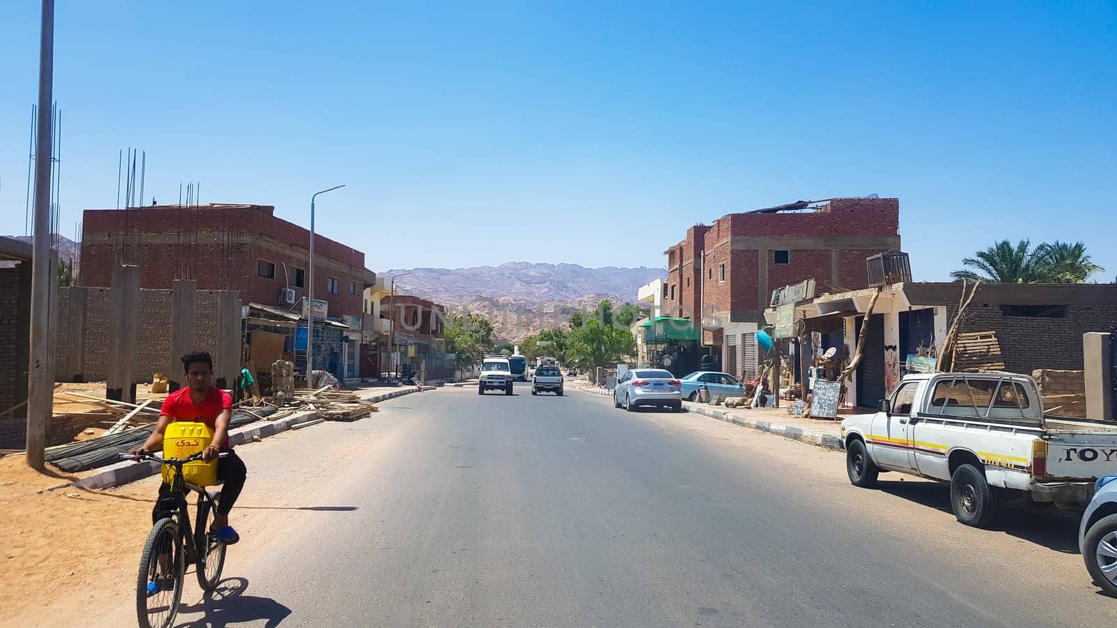 Egypt, Dahab - June 20, 2019: an Arab riding a bicycle along one of the streets of Dahab. Desert Street. Egyptian residential buildings. The city of Dahab