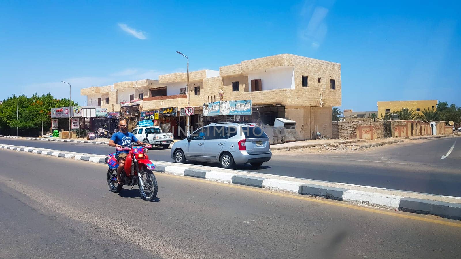 Egypt, Dahab - June 20, 2019: an Arab riding a scooter along one of the streets of Dahab. Desert Street. Egyptian residential buildings. The city of Dahab
