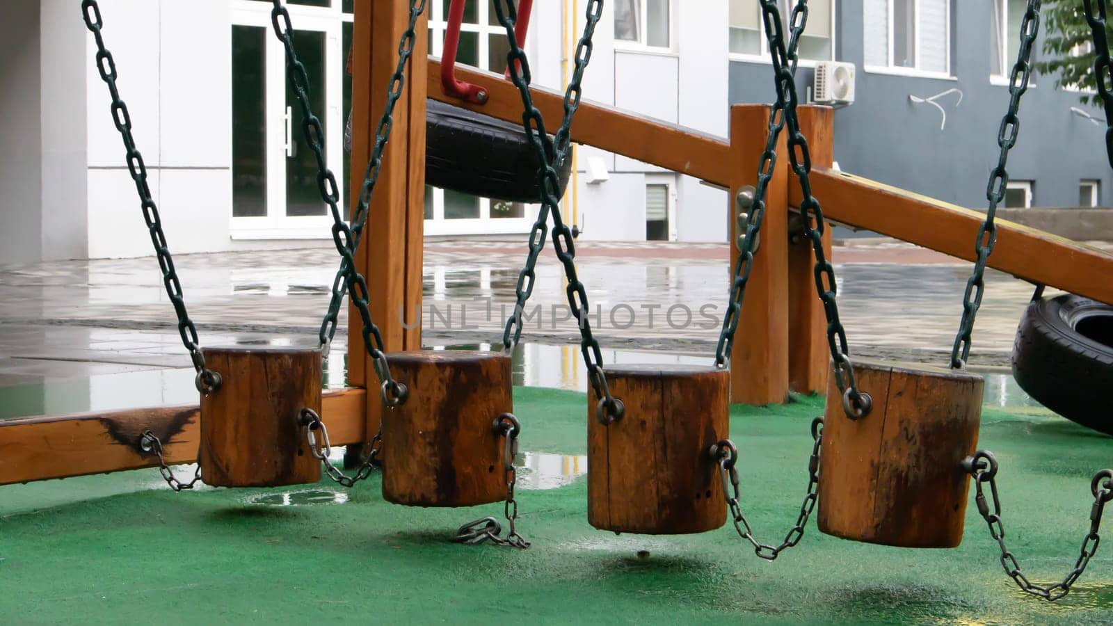 A courtyard of high-rise buildings with a modern and large playground made of wood and plastic on a rainy summer day without people. Empty outdoor playground. A place for children's games and sports