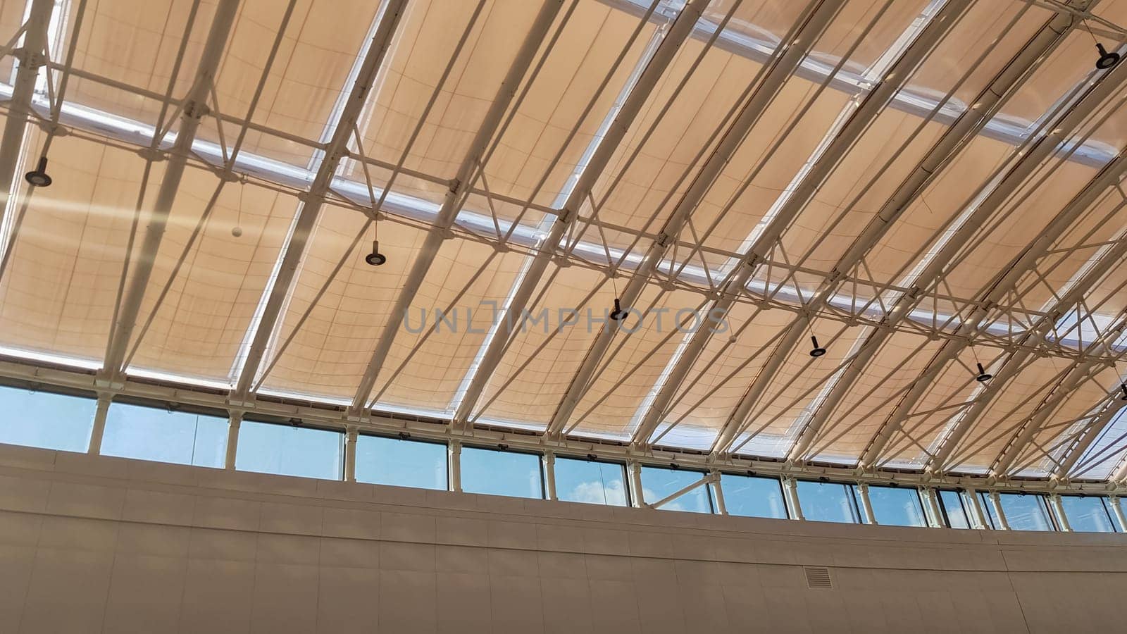 Curved roof with windows of a large shopping center indoors. Modern metal and glass ceiling construction