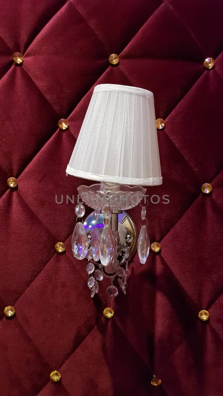 Retro bedroom lamp with a red wall. Antique sconces hanging on a wall of textile with buttons