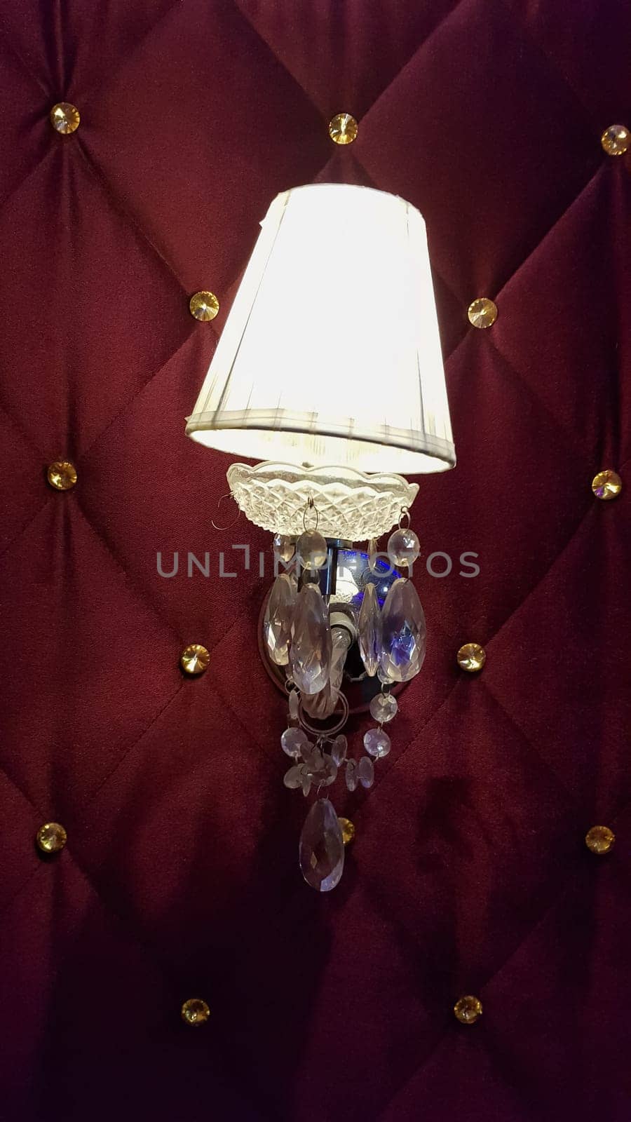 Retro bedroom lamp with a red wall. Antique sconces hanging on a wall of textile with buttons