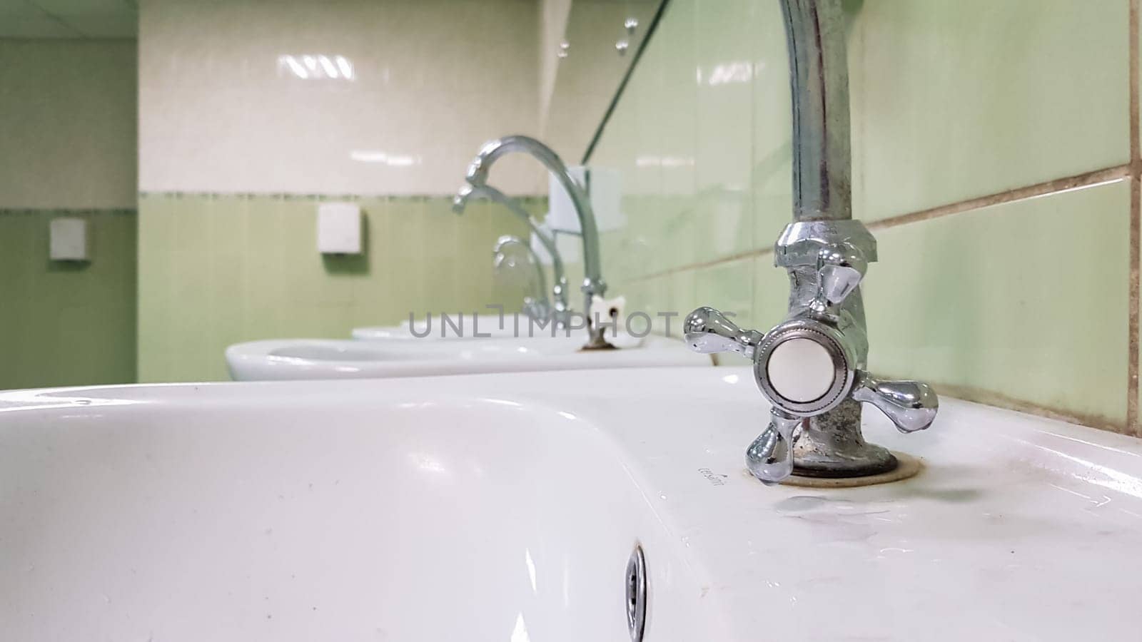 Old and dirty faucet and white ceramic washbasin sink, concept of cleaning, repairing or replacing a bathroom, toilet