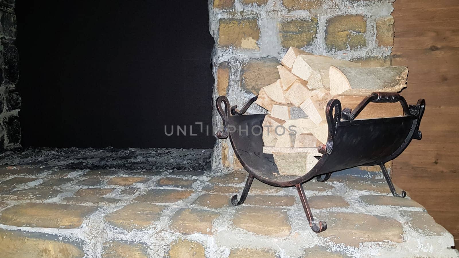 A pile of wood near a stone fireplace indoors. Winter holiday. Winter and romance concept