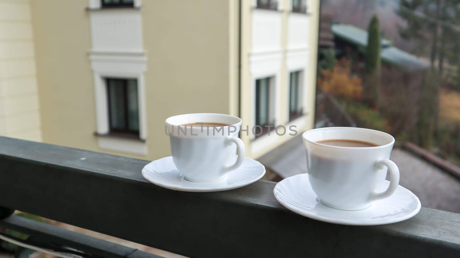 Two coffee cups on a balcony with mountain landscape in the morning. Two cups of morning coffee, standing on the side of the balcony, with a magical view of the autumn forests