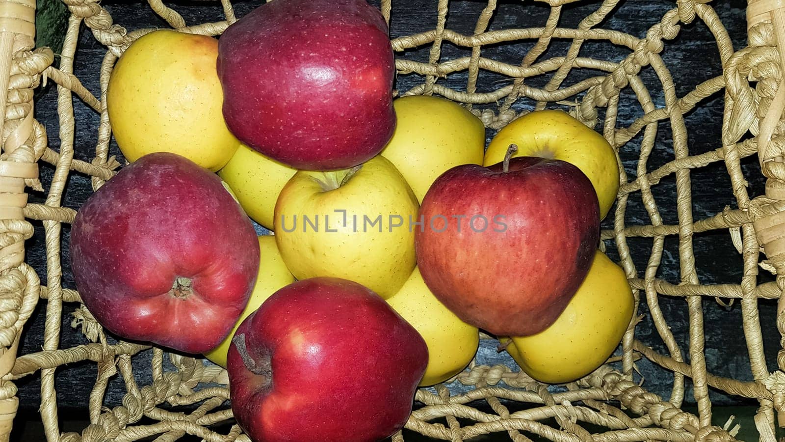Red and green apples in a basket in a dark key and home decor
