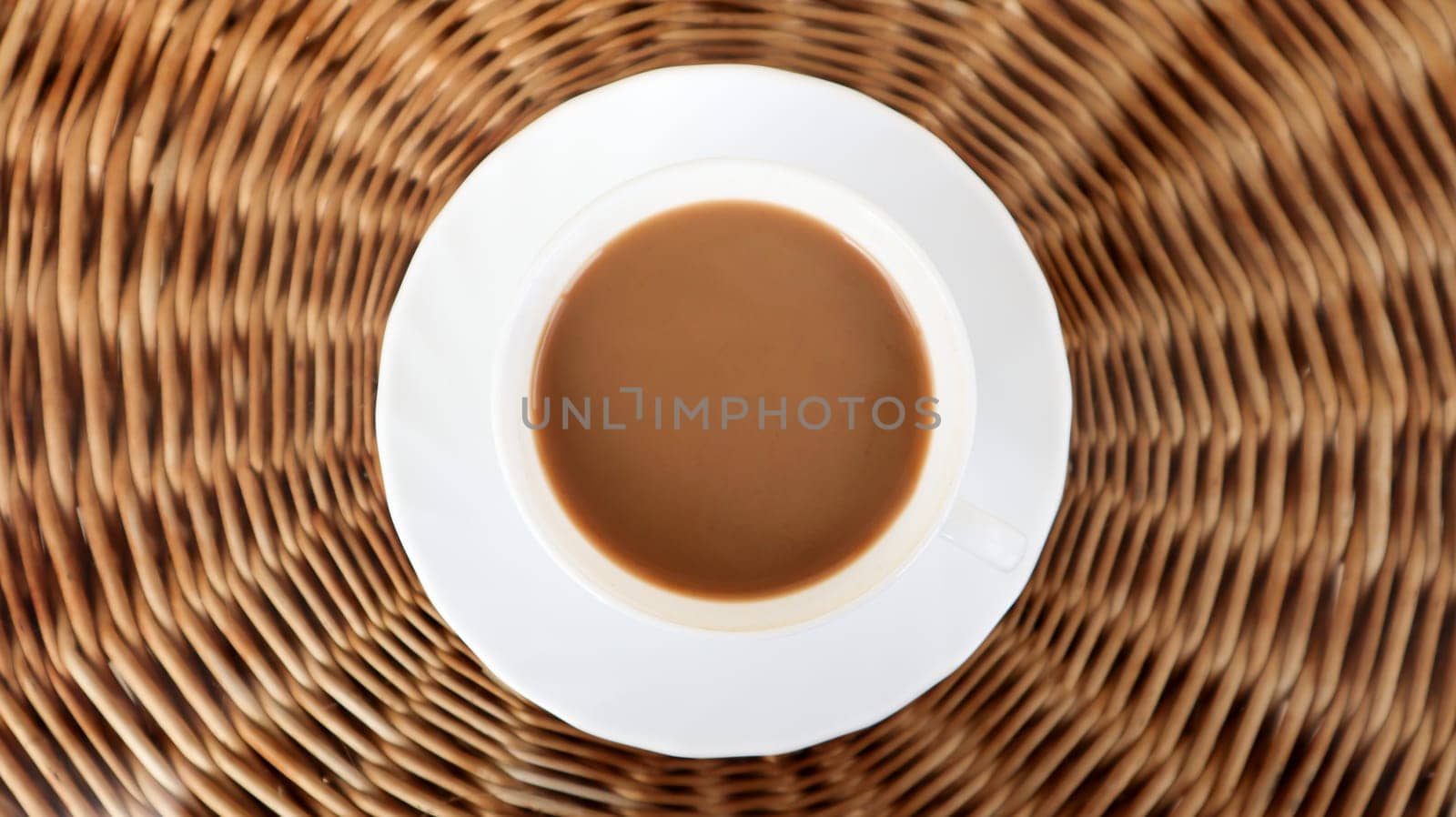 Coffee cup on wicker background top view. Hot aromatic coffee with milk. Freshly prepared drink is served in a modern cup on a light wicker table.
