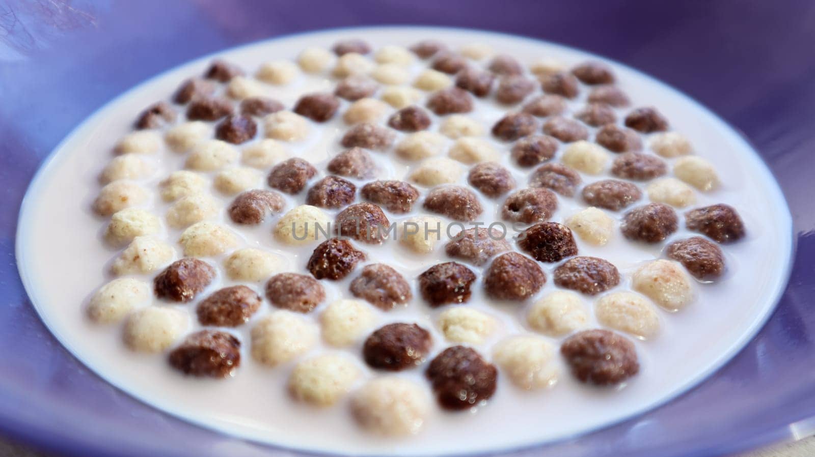Healthy breakfast with milk on the table in a deep plate. Whole grain chocolate and milk balls. Healthy cereal breakfast. Children's breakfast. Baby food. Balanced diet. Dry ready and quick snack.
