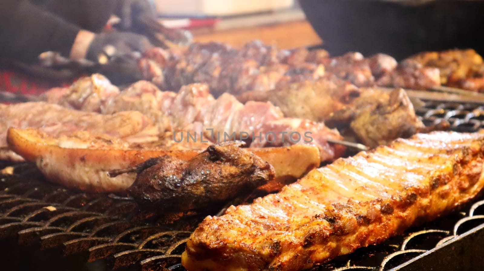 Fried pork ribs. Grilled pork kebabs on a teapot. Barbecue Kid on the grill. grilled kebab, kebab. Festival of delicious fried street food. The meat on the bone, the cooking process.