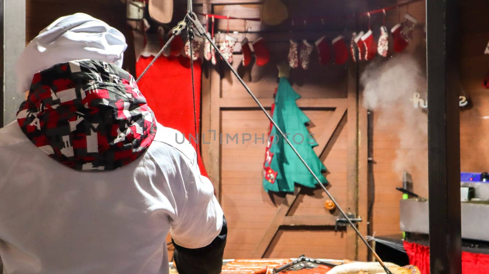 The chef cooks grilled kebabs, street food, culinary feast. Fresh sausage and grill outdoors. A man is preparing street food of German cuisine. Christmas market in Europe. Festival City Fair.
